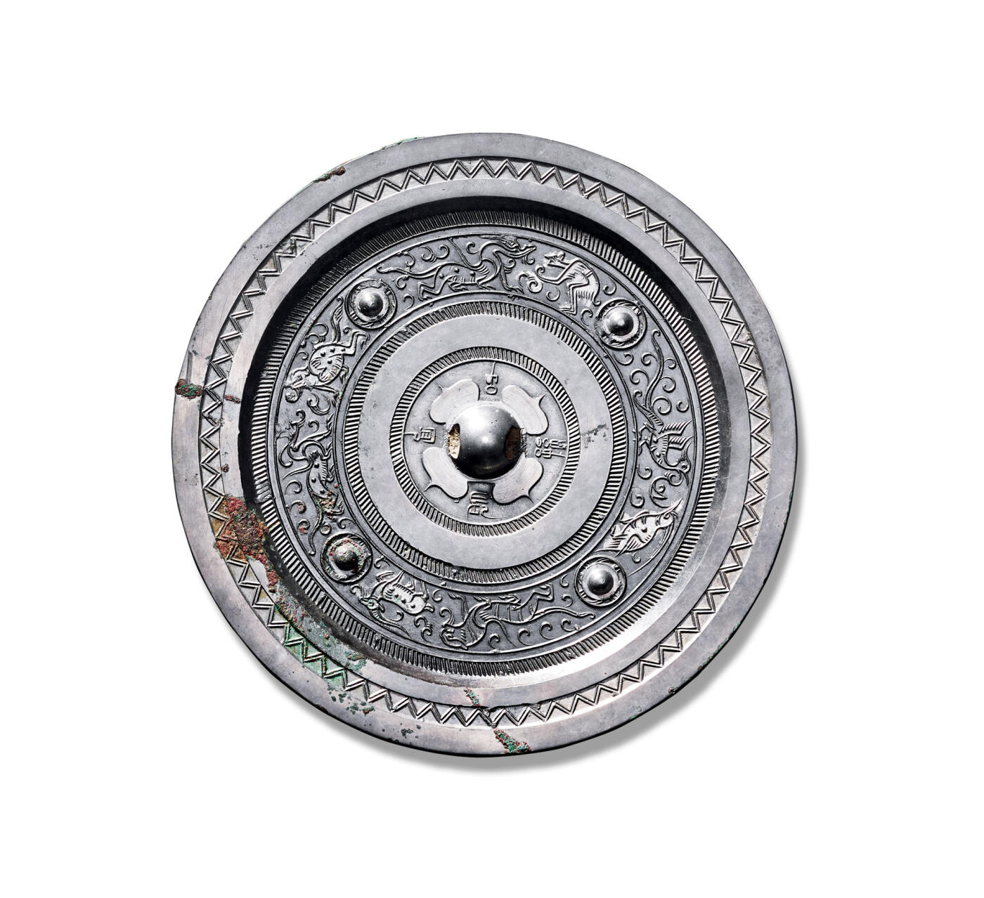 上海匡时2025年秋季拍卖会 中国历代钱币 铜镜专场 四乳烫银八兽镜 圆形，圆钮，柿蒂纹钮座。钮座外围环饰“长宜子孙”四字铭文，其外设一周宽凸棱。主题纹饰以四枚乳钉为界，将镜背划分为四区，分别饰有：羽人戏青龙、白虎逐独角兽、朱雀吻凤鸟，以及长尾蟾蜍与青龙相嬉。其中羽人、独角兽、凤鸟与蟾蜍等纹饰局部烫银，装饰效果独特。镜缘宽平，饰一周双线锯齿纹。此镜通体银白光洁，铜质精良，版模规整，铸工精湛。