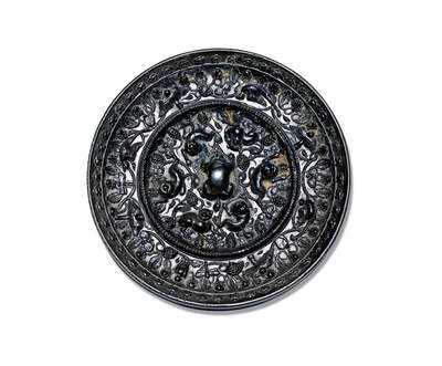 上海匡时2025年秋季拍卖会 中国历代钱币 铜镜专场 - 海兽葡萄镜 圆形，伏兽钮。镜背由一道凸起的高圈将纹饰分为内外两区：内区六只瑞兽环钮而踞，或回首顾盼，或昂首阔步，形态各异，动态丰富，造型浑朴而富有生机。瑞兽间饰以葡萄枝叶与雀鸟纹样，枝叶穿插缠绕，布局优美流畅。外区葡萄藤蔓与禽鸟相间分布，布局精细。镜黑漆古，光气匀亮，葡萄枝叶过梁，浮雕挺立，工艺细腻，保存完整。