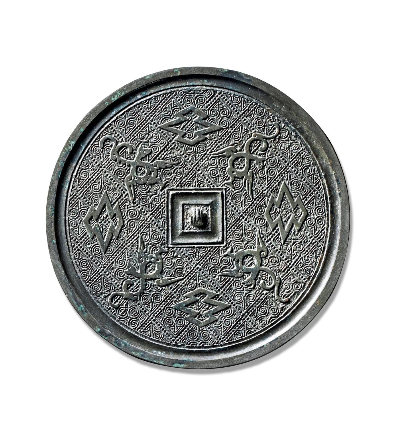 上海匡时2025年秋季拍卖会 中国历代钱币 铜镜专场 四凤菱纹镜 圆形，三弦钮，方钮座，钮外饰双线凹面方框。纹饰以三角形雷纹、云纹、连珠纹、花朵与花叶纹构成连续布局的底纹，其上四凤纹与四菱纹相间分布，排列有序。整体纹饰少见，刻画精美，铸工精细，铜质精良，展现出了楚风文化的大气与华丽。