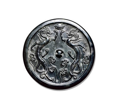 上海匡时2025年秋季拍卖会 中国历代钱币 铜镜专场 - 双龙镜 圆形，圆钮。镜背主题纹饰为双龙隔钮相对，身修长，四肢伸张，呈跃欲动飞跃之势。龙首上方，各举前肢，共托宝莲。龙纹整体造型巧妙，布局饱满。纹饰刻画细腻入微，龙首犄角分明，五官清晰可见，神态鲜活，张口吐舌，双目直视，鳞甲清晰，背鳍、腹甲、鳞片、龙尾均刻画细密，龙爪劲健，伸向四方。强健的龙体和修长的四肢具有独特卓异的动律美、节奏美和力度美。<br>背铸龙纹若凌空腾起，犹似白居易「背有九五飞天龙，人