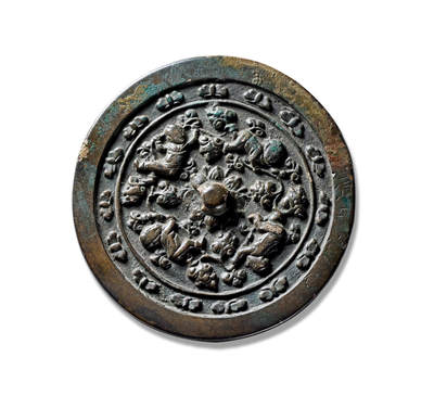 上海匡时2025年秋季拍卖会 中国历代钱币 铜镜专场 - 童子戏莲镜 圆形，圆钮，经典童子戏莲题材铜镜，采用高浮雕的表现技法。镜背满铺莲花花叶纹饰，刻画精细，叶脉清晰，繁郁葱茂，莲花纹上铸饰四位童子形象面目清晰，稚嫩可爱，身着童衣，形态各异，趴伏嬉戏，极富趣味。镜背呈现出一副极具生活气息的婴戏图景，“婴戏”题材为这一时期较为经典的一个艺术主题，且应用颇广，最早即被具有独特艺术气息的文人雅士所捕捉并运用在绘画艺术上，体现了对孩童的无限关爱与期望，又表达了古