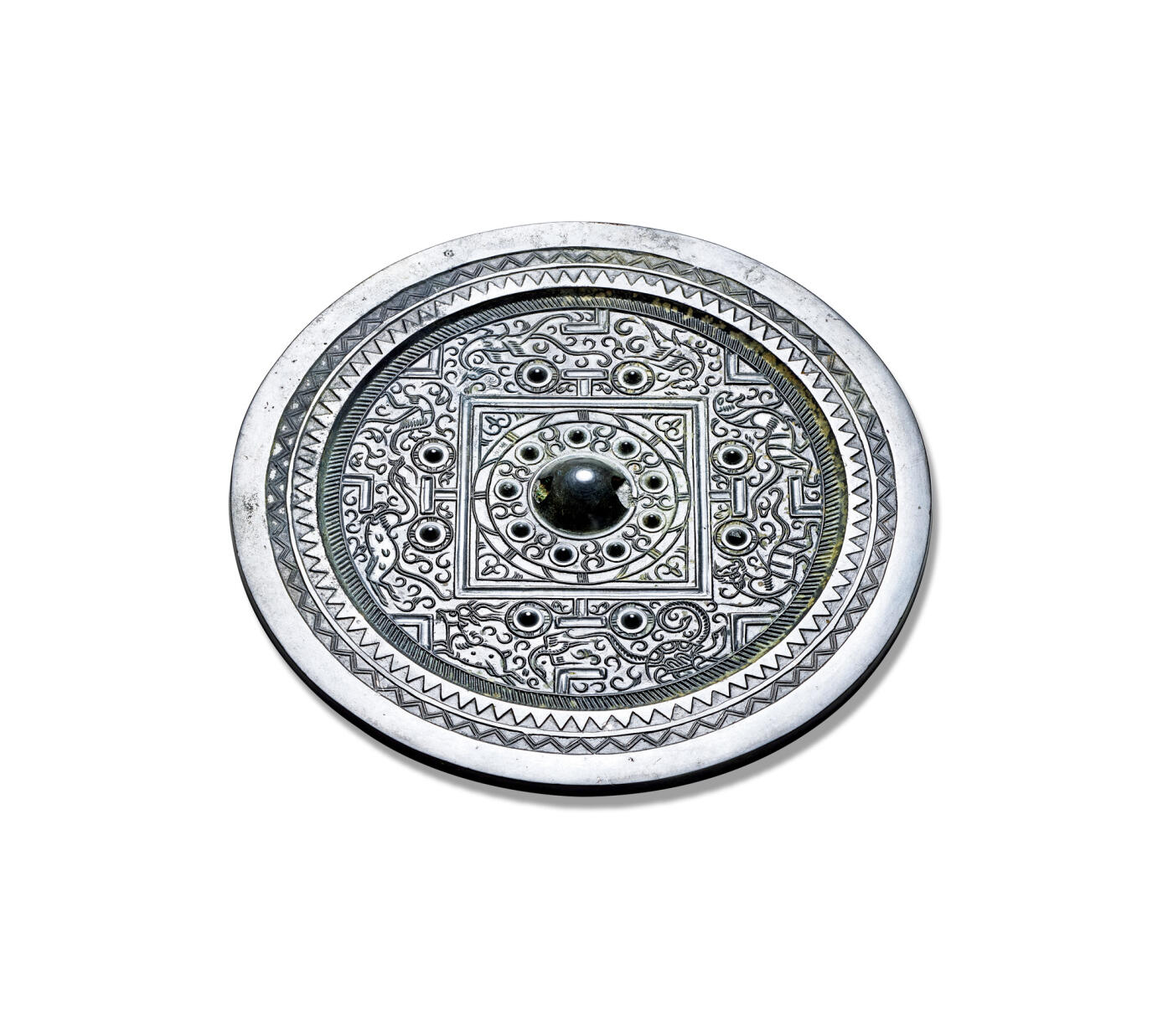 上海匡时2025年秋季拍卖会 中国历代钱币 铜镜专场 四灵神兽规矩镜 圆形，圆钮，圆钮座。镜背内外区饰有九枚带座乳钉，以几何纹间隔。双线凹面方格内四角装饰八组半圆卷叶纹。四“T”纹两侧配以圆钮座八乳钉，并与博局纹共同将主纹饰划分为四方八区，区内饰四灵及一神兽。其外环饰一周栉齿纹。镜缘宽平，上饰锯齿纹，沿边处另饰双线齿纹。整镜纹饰精美，线条细腻，流畅灵动。整镜通体呈黑漆古，收藏级品相。