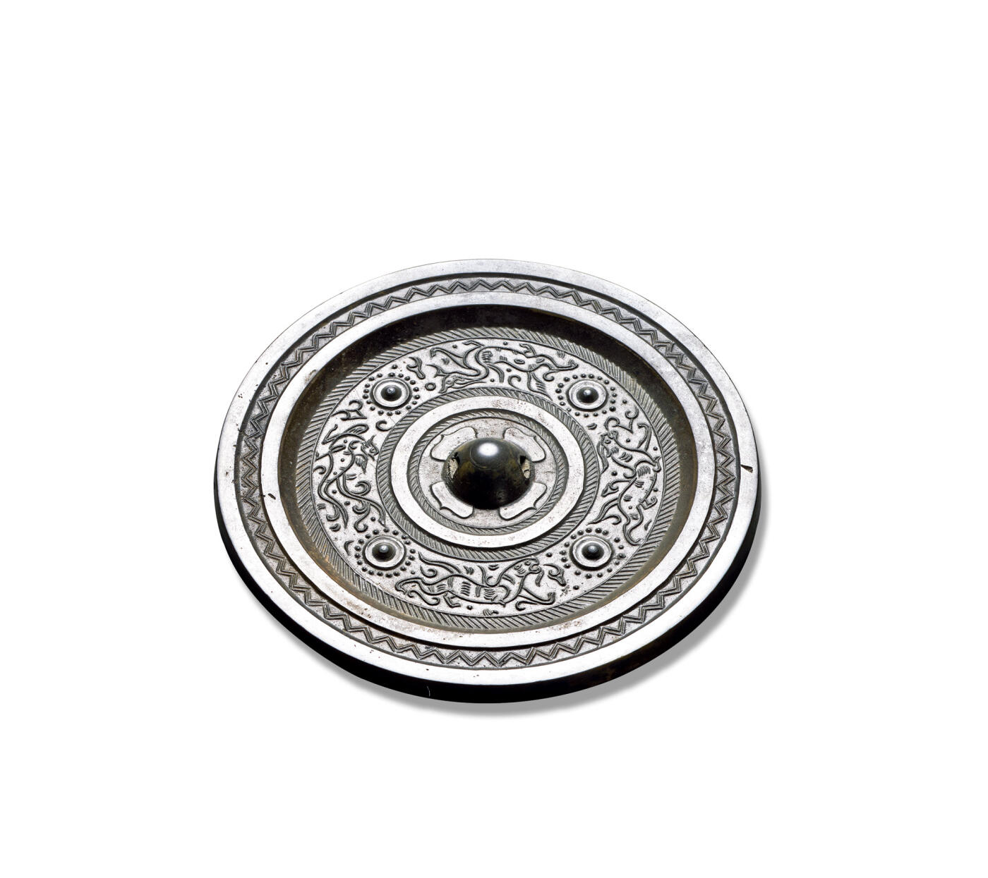 上海匡时2025年秋季拍卖会 中国历代钱币 铜镜专场 四乳四兽镜 圆形，圆钮，柿蒂纹钮座。钮座外装饰一周凸弦纹，外有两周栉齿纹环绕主纹饰，带座四乳钉将纹饰分为四区，其间装饰青龙、白虎与朱雀，线条简单，极具生动，镜缘饰以一周双线锯齿纹。金闻德评级：92，带木盒。