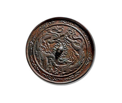 上海匡时2025年秋季拍卖会 中国历代钱币 铜镜专场 - 双龙纹镜 圆形，圆钮，火焰花形钮座。钮座外双龙踏云而起，首尾相衔，环绕镜钮。龙首微颔，双目有神，长嘴翘唇，颚下髯须丰密；龙身如蛇，劲健舒展，颈曲背耸，鳍列整齐，通体饰斜格鳞纹，线条流畅自然。四肢修长，关节处生柔韧翼翅，龙爪如鸟，肥硕锋利，呈弯三角状，刚中带柔。镜缘饰八朵祥云纹，衬托出主纹的雄健磅礡、庄严灵动。整体构图饱满，铸工精湛。双龙镜在古代较为少见，存世稀罕，此镜尺寸硕大，保存完好，皮壳温润熟