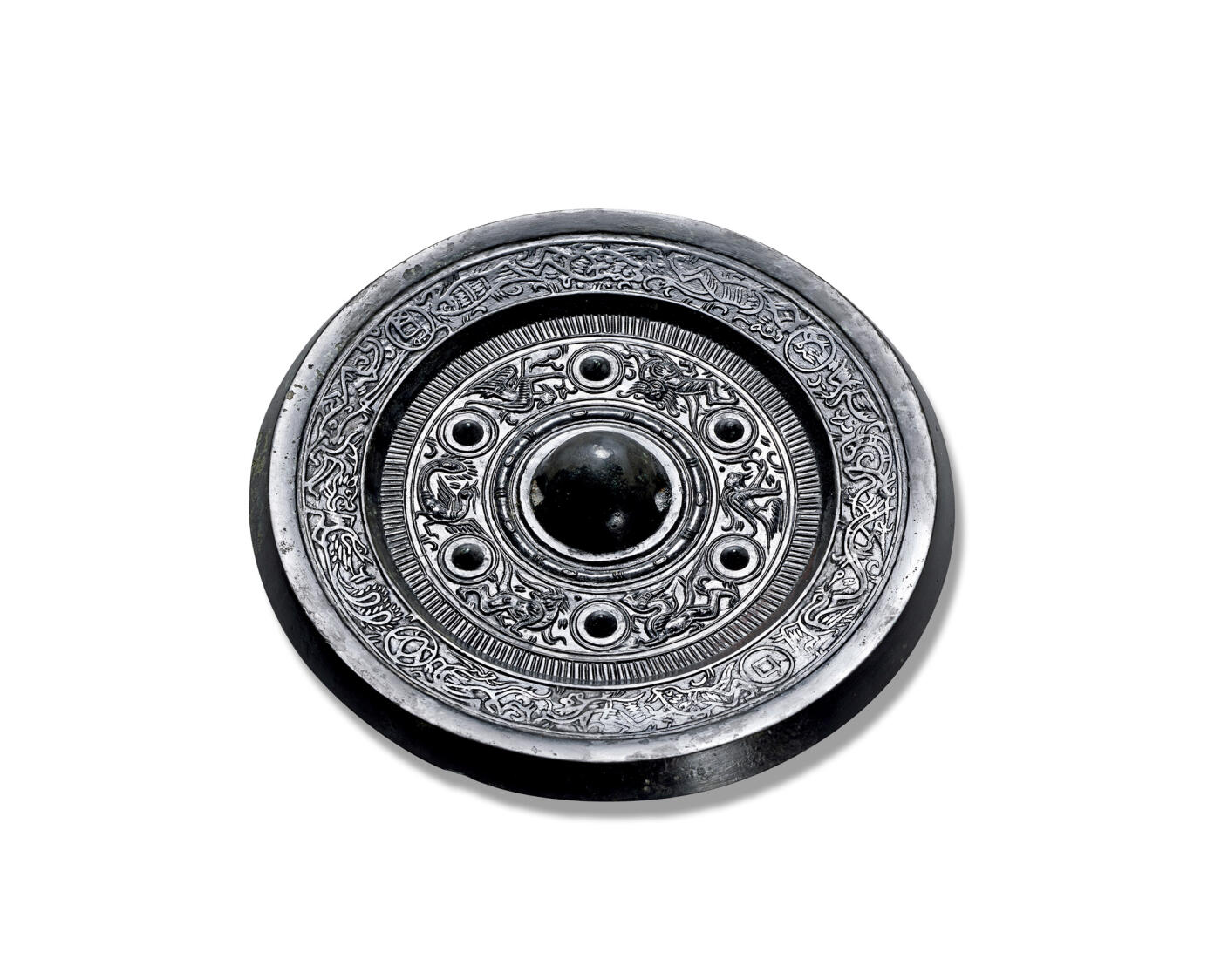 上海匡时2025年秋季拍卖会 中国历代钱币 铜镜专场 动物钱纹边饰六乳瑞兽镜 圆形，圆钮，圆钮座，钮座外环绕凸弦纹圈带及栉齿纹。主纹饰区以六枚圆座乳钉将主纹饰六等分，分别雕铸青龙、獬豸、羽人、朱雀、鸾鸟等神人瑞兽，线条婉转流畅，刻画精细，装饰意味颇浓。近缘处饰以变形的青龙、白虎、朱雀、玄武四神及羽人、鱼及其它瑞兽组成，纹饰间间隔五铢钱纹及蟾蜍、阳乌等，体态舒展，相互追逐。多乳瑞兽纹镜之中，七乳居多，六乳相对少见。此镜通体黑漆古，铸造精良，纹饰清晰而无