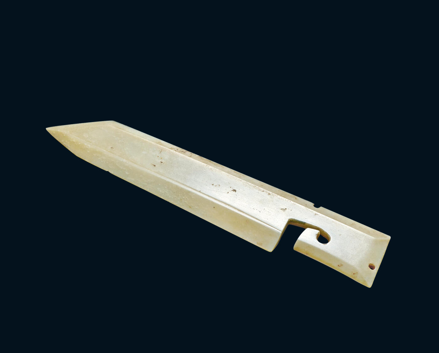 上海匡时2025年秋季拍卖会 中国历代钱币 铜镜专场 玉戈 玉戈，玉质清润，玉色纯透，光滑净彻。体扁平，援下部有一随形凸脊，斜刃，一边略成弧形，戈锋尖锐，锋呈三角形。近援处居中有一钻孔。通体光素无纹，磨制光洁，形制规整。