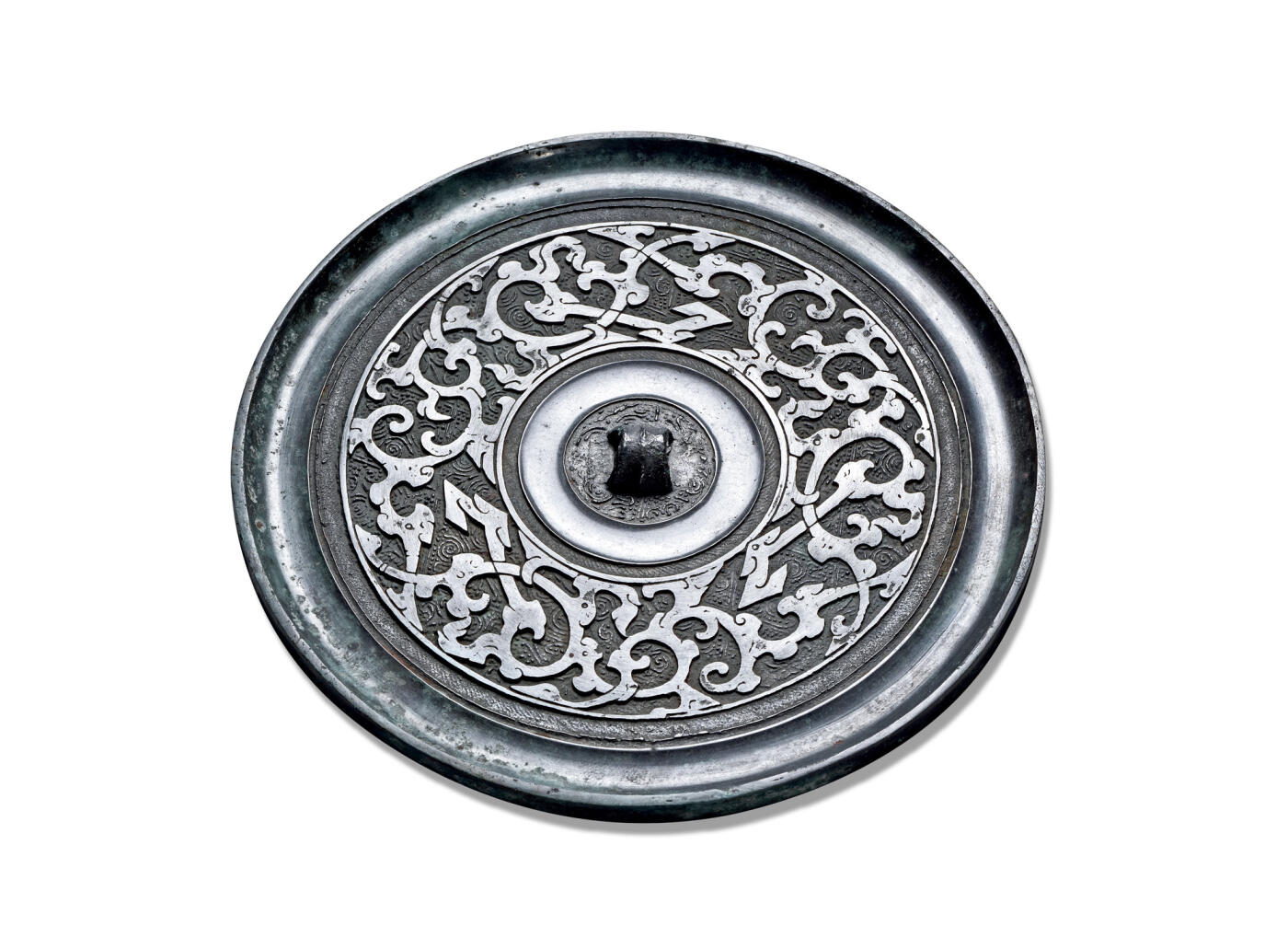 上海匡时2025年秋季拍卖会 中国历代钱币 铜镜专场 蟠螭纹镜 圆形，三弦钮，圆钮座，素缘卷边。钮座外为一周凹面环形宽带，带内满饰细密的云雷纹。外区纹饰分为两层：以细密清晰的云雷纹为地纹，其上以宽平凸起的粗线勾勒出三条蟠曲缠绕的蟠螭纹，作为主纹。此镜纹饰布局层次分明，铸造精美。云雷地纹细密规整，有效衬托出主纹的立体与华美，整体呈现出古朴而华丽的艺术风格。