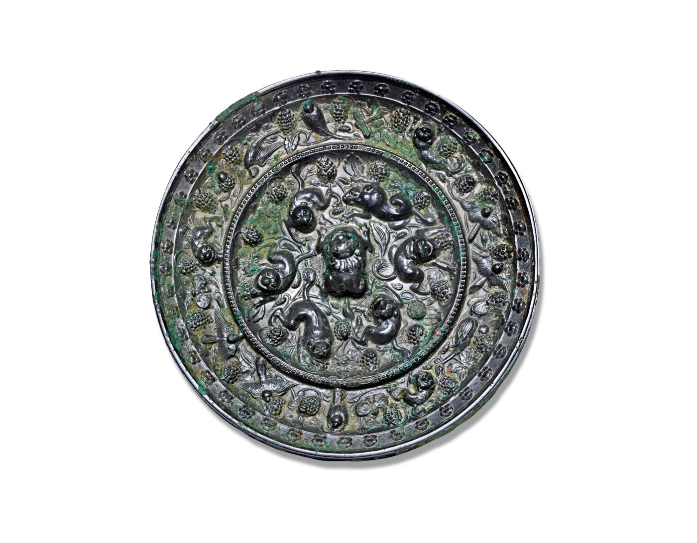 上海匡时2025年秋季拍卖会 中国历代钱币 铜镜专场 海兽葡萄镜 圆形，伏兽钮。镜背由一圈凸梁分隔为内外两区。内区饰高浮雕瑞兽六只，环钮而踞，姿态各异：或回首顾盼，或昂首前行，造型顽皮生动，极富自然意趣。内外区均满铺葡萄藤蔓纹饰，果实饱满，枝叶扶疏，藤蔓虬曲蜿蜒，布局繁密而不失灵动，细腻中见生机。镜缘高耸，缘面缓倾，上饰连续排列的卷云，为整体增添庄重与韵律之美。