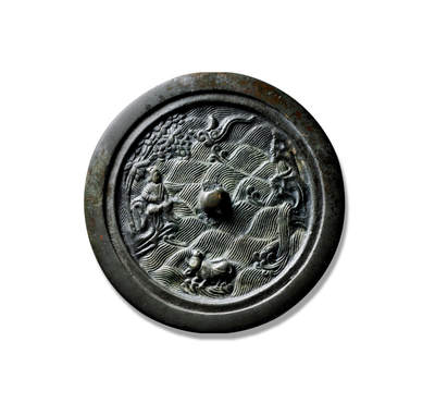 上海匡时2025年秋季拍卖会 中国历代钱币 铜镜专场 - 犀牛望月仙人故事镜 圆形，圆钮。镜钮上部云纹顶端皆呈如意云头状，云间托一弯新月，钮下水波纹之中一岛屿，一头牛安详的跪卧其上，回首望月。镜钮左侧山间岩凳上一仙人端坐，凝视对面嶙峋山石间飞流直下的瀑布，仙人背后一枝繁叶茂的树，树冠横伸至仙人头顶上方。此镜在纹饰设计方面由于大面积海水纹的精心布置使得镜背有主有次，颇有“春江潮水连海平，海上明月共潮生”的意境。近缘处另设一层台面使得此镜颇显厚重之感，镜背满