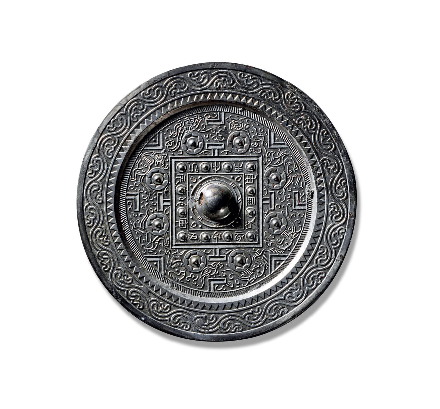 上海匡时2025年秋季拍卖会 中国历代钱币 铜镜专场 四灵神兽规矩镜 圆形，圆钮，圆钮座。双线凹面方格内饰几何纹，四边各排列十二枚圆座乳钉，乳钉间篆书十二地支铭文相间。四“T”纹两侧配以连弧纹座八乳钉，与规矩纹共同将主区划分为四方八区。除青龙、白虎、朱雀、玄武四神之外，更饰有羽人、羚羊、独角兽、舞蹈蟾蜍等较为罕见的祥瑞纹样。神兽形体皆以流畅线条勾勒，造型灵动，意趣盎然，展现出丰富而奇逸的想象力。主纹外环饰一周栉齿纹，宽厚的平缘上依次饰有锯齿纹与双线水