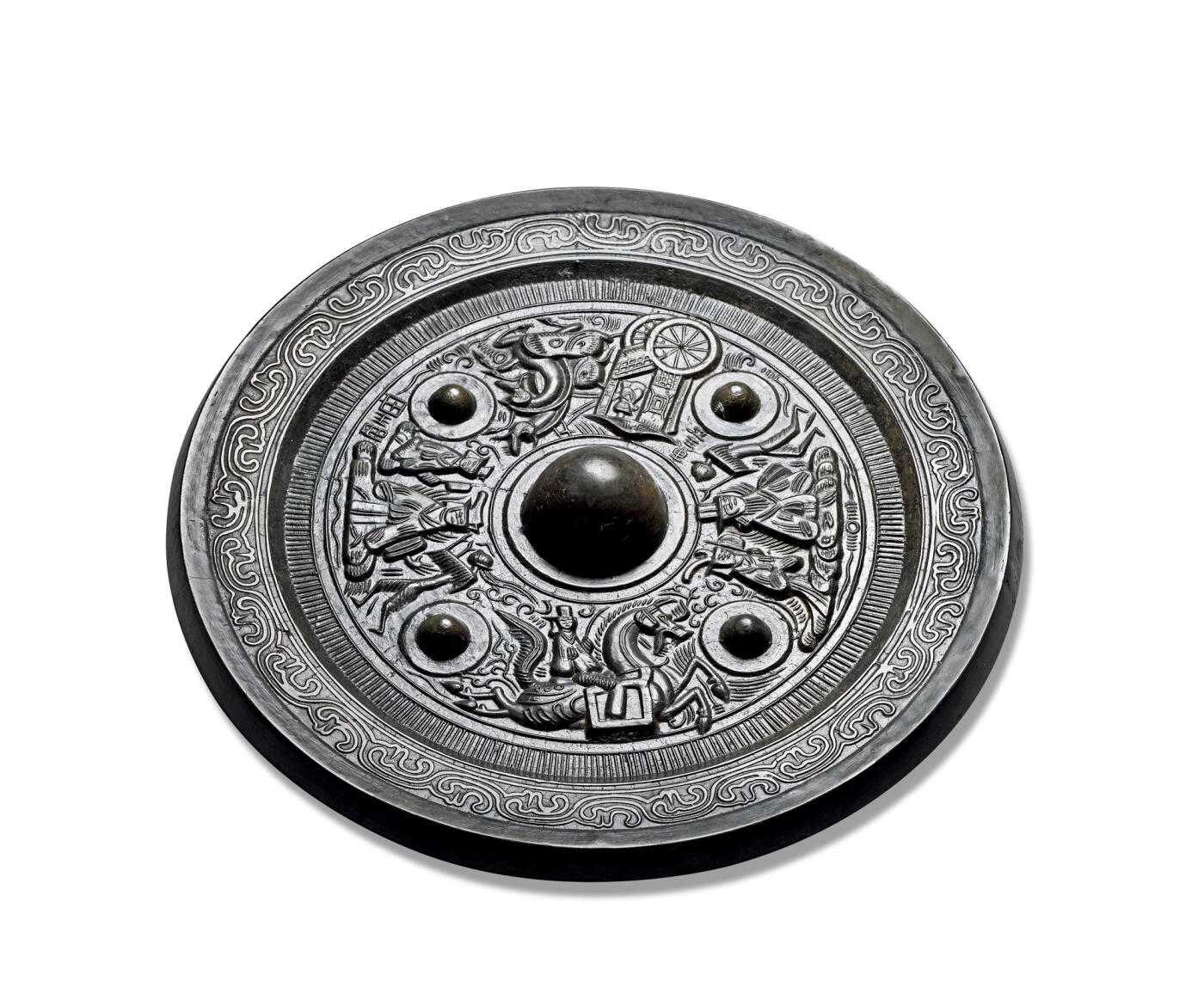 上海匡时2025年秋季拍卖会 中国历代钱币 铜镜专场 神人神兽车马画像镜 圆形，圆钮，双圈弦纹圆钮座。四枚大型圆座乳钉，将主纹饰分为四组。最下一组为东王公，头戴三山冠，双手袖于胸前，后有侍者相伴，前方有一羽人引路和一“王公”铭；最上一组为东王母，头饰双发髻，双手袖于胸前容貌端详，前后有羽人和侍从侍奉，后下有“西王母”铭，左区一组为羽人骑战马。相对一组为骏马驾车，车内坐一神人。主纹饰外一周栉齿纹。宽外缘上饰云气纹。此镜黑漆古，版模精，尺寸大，品相佳，惜