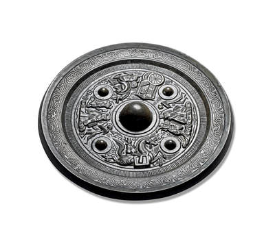 上海匡时2025年秋季拍卖会 中国历代钱币 铜镜专场 - 神人神兽车马画像镜 圆形，圆钮，双圈弦纹圆钮座。四枚大型圆座乳钉，将主纹饰分为四组。最下一组为东王公，头戴三山冠，双手袖于胸前，后有侍者相伴，前方有一羽人引路和一“王公”铭；最上一组为东王母，头饰双发髻，双手袖于胸前容貌端详，前后有羽人和侍从侍奉，后下有“西王母”铭，左区一组为羽人骑战马。相对一组为骏马驾车，车内坐一神人。主纹饰外一周栉齿纹。宽外缘上饰云气纹。此镜黑漆古，版模精，尺寸大，品相佳，惜