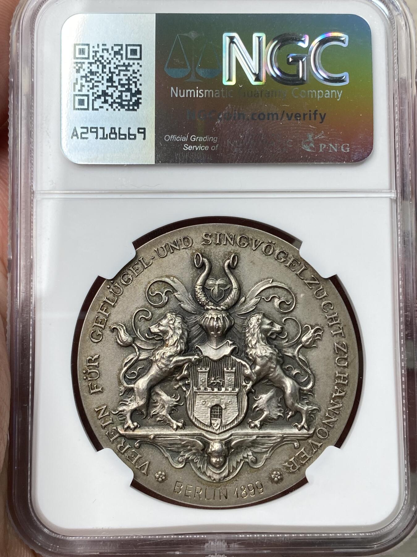 万国钱币拍卖第057期（万国冬季大拍） NGC MS64 1899年德国银章 汉诺威家禽养殖协会 柏林造币厂 唯一记录冠军分 少见品种 高浮雕，细节爆表，雕刻精致，栩栩如生。磨砂精铸，豪华纹章，实物极美。正面:农场少女给动物们喂食。欢快小鸟，开屏孔雀，公鸡母鸡小鸡，大小鸭子。幽兰芳草，勃勃生机，自然美好和谐。背面:汉诺威城市纹章。精美奢华的洛可可风格。双狮拱卫骑士三叶草头盔盾徽，底部双翼天使。汉诺威双狮纹章之精美无出其右。