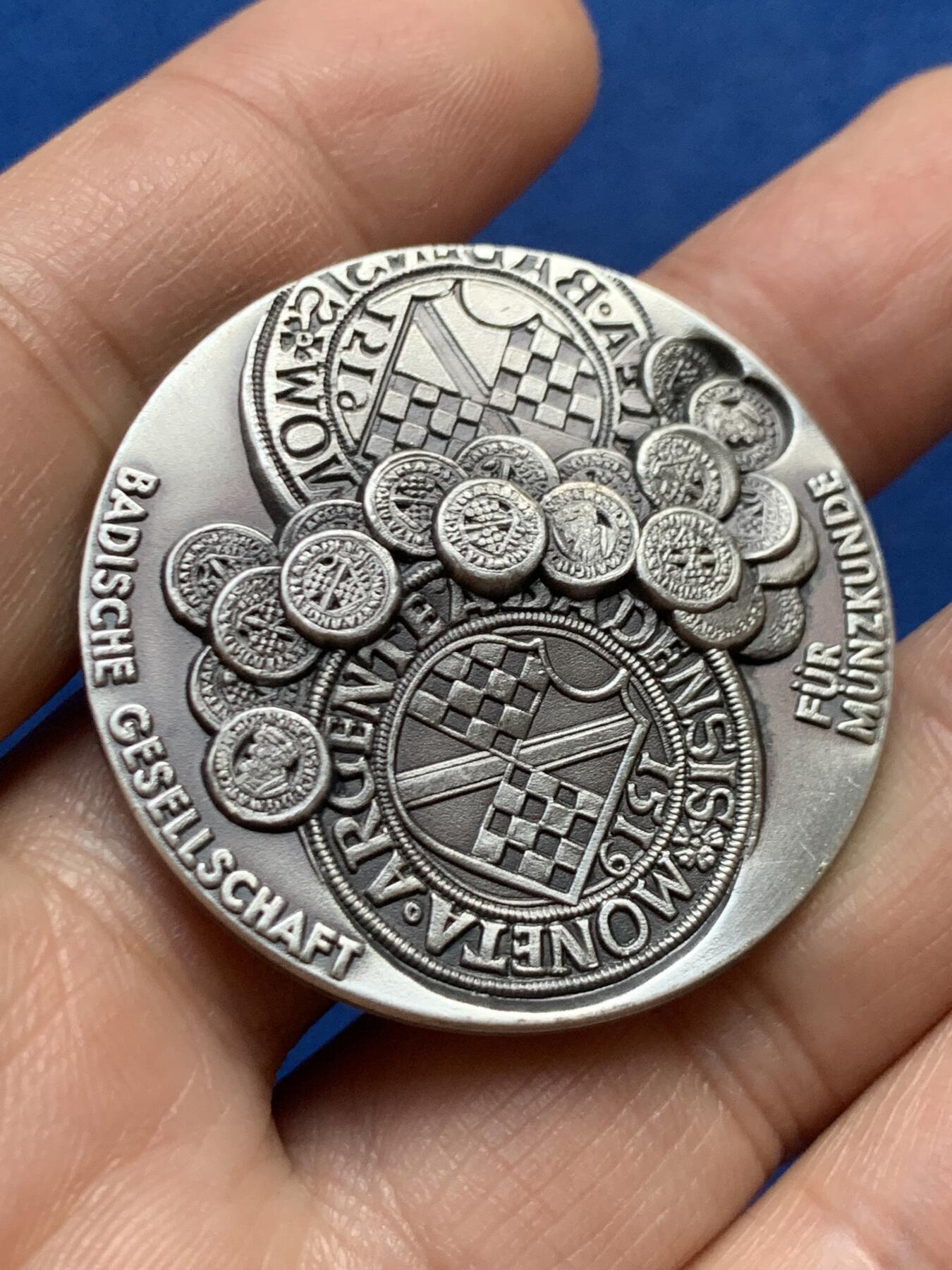 《竞宝斋》第447场 周日，周一，2场连拍 （全场包邮） 德国巴登地区货币历史纪念纯银银章 该章上环绕着多枚小型仿古钱币浮雕，这些是历史上巴登地区流通的货币样式，展示了该地区货币发展的多样性与历史脉络。35.3克，40.2mm，带边铭，双面高浮雕。