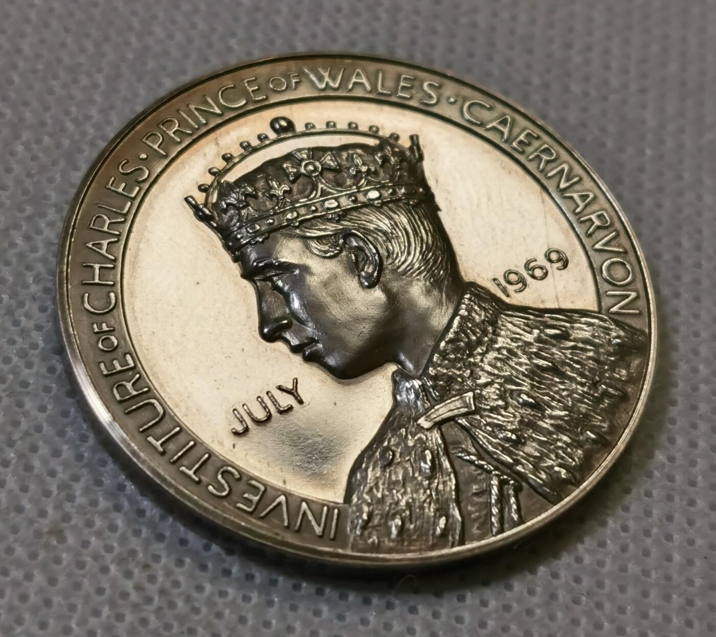 甄臻铺-世界币章拍卖（第44期）精品场拍品征集中，送拍享返佣金等优惠多多 1969年英国威尔士亲王查尔斯加冕纪念银章，直径38.6毫米，重26.6克，边缘有编号313。正面是查尔斯亲王侧像，JULY 1969字样，背面是卡那封城堡和威尔士龙，CAERNARFON字样，整体浮雕工艺精细，镜面底板，模具压制到位。这枚银章是英国皇室历史的重要见证，查尔斯亲王加冕仪式在卡那封城堡举行，意义重大。细节见图
