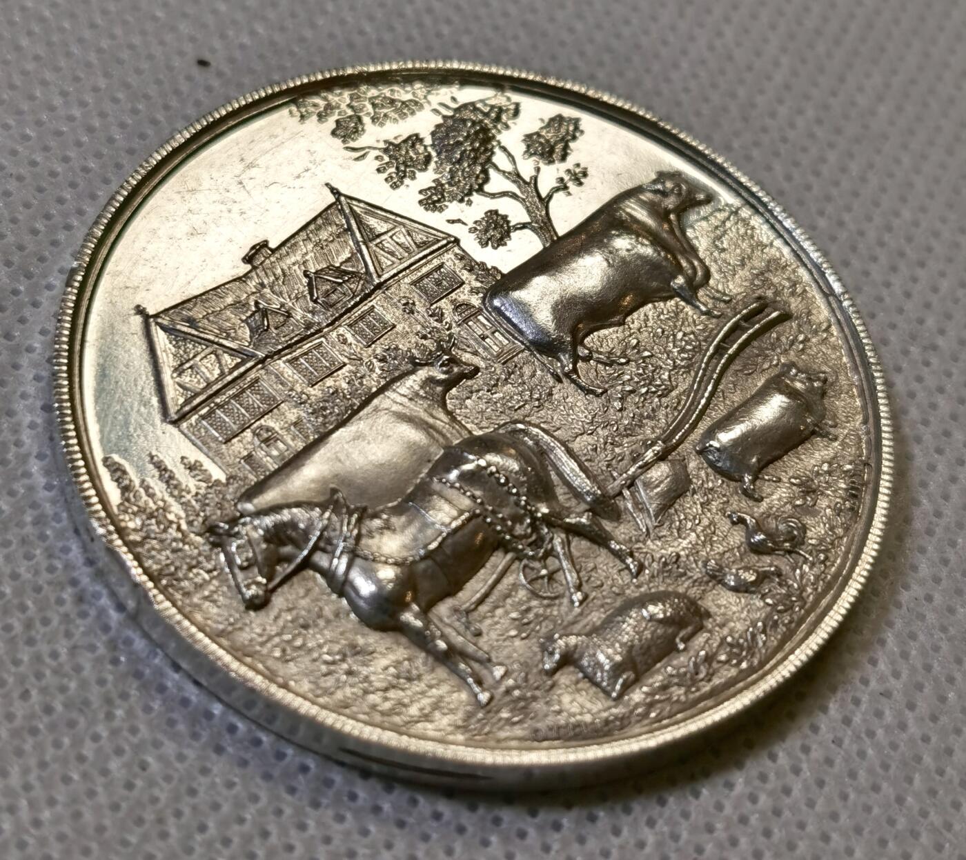 甄臻铺-世界币章拍卖（第44期）精品场拍品征集中，送拍享返佣金等优惠多多 19世纪英国Spalding农业与马术展览会纪念银章，直径47.3毫米，重37.4克，精美浮雕工艺。正面刻画农庄场景，两头牛和马匹，背景是传统英式建筑，周围环绕麦穗花环装饰。背面刻有