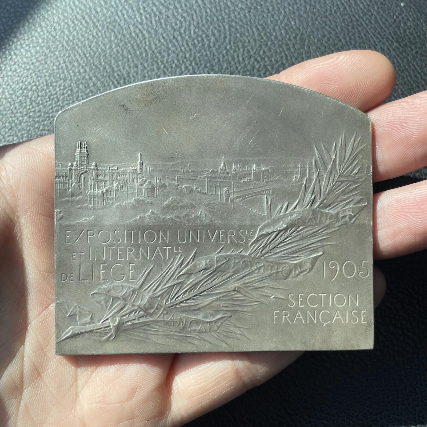 「木头集藏」“冬至雅藏”——章牌精品专场！ F. Vernon～法国银章 1905年比利时列日世博会，尺寸：63 x73mm，139 g，边铭：1 丰饶角 ARGENT。铜章较常见，银章非常罕见。正面是比利时女神在欢迎法国女神玛丽安娜，背面是世博会场馆。1905年世博会在比利时列日举办，以庆祝比利时王国独立70周年。此章由负责法国在境外参展事宜的“法国海外展览委员会”委托铸造。