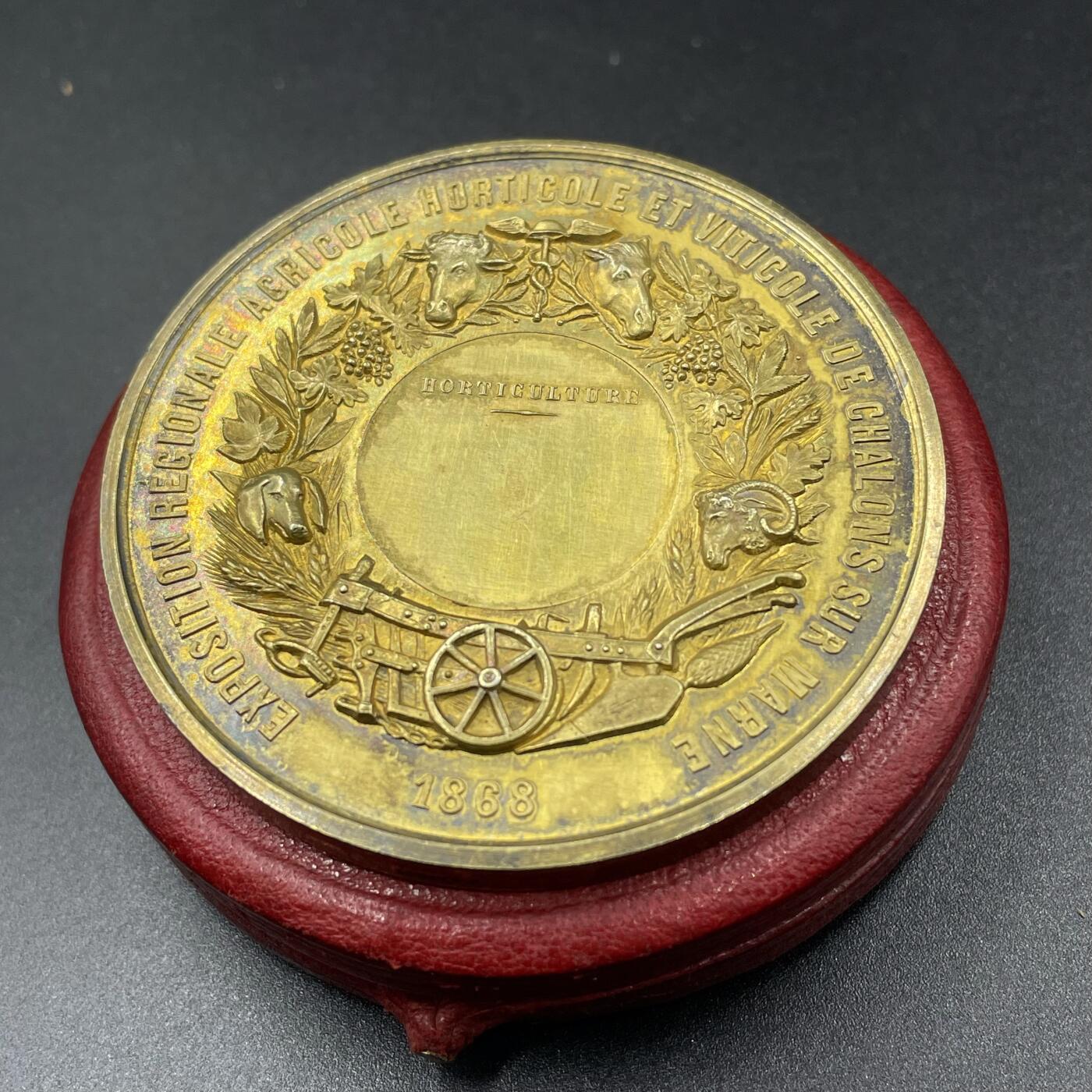 「木头集藏」“冬至雅藏”——章牌精品专场！ A.MERLEY.F～1868年法国马恩河畔沙隆地区农业、园艺与葡萄种植博览会原盒镀金大银章，直径：57.2 mm，88.2 g，边铭：蜜蜂 ARGENT，品相很不错，原盒正常扣合（打开略吃力），章面装饰有牛、马、羊等牲畜头雕，搭配葡萄藤、麦穗等农业元素，还有犁、车轮等农具图案，正中刻有“HORTICULTURE”（园艺），直观体现博览会聚焦农业、园艺与葡萄种植的主题。