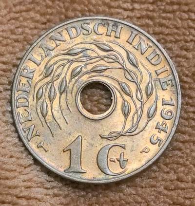 外国优质老铜币高银银币，周六九点倒数截拍，满百包邮，持续收拍 - 带原光荷属东印度1945 年P版壹分，中间有圆孔。正面环绕 “NEDERLANDSCH INDIE 1945” ，以稻穗图案呈现，呼应殖民地农业；背面是爪哇文与马来文（爪夷文 ），搭配花卉元素，见证二战后荷兰殖民历史与印尼多元文化，具历史、收藏及殖民文化研究价值 。