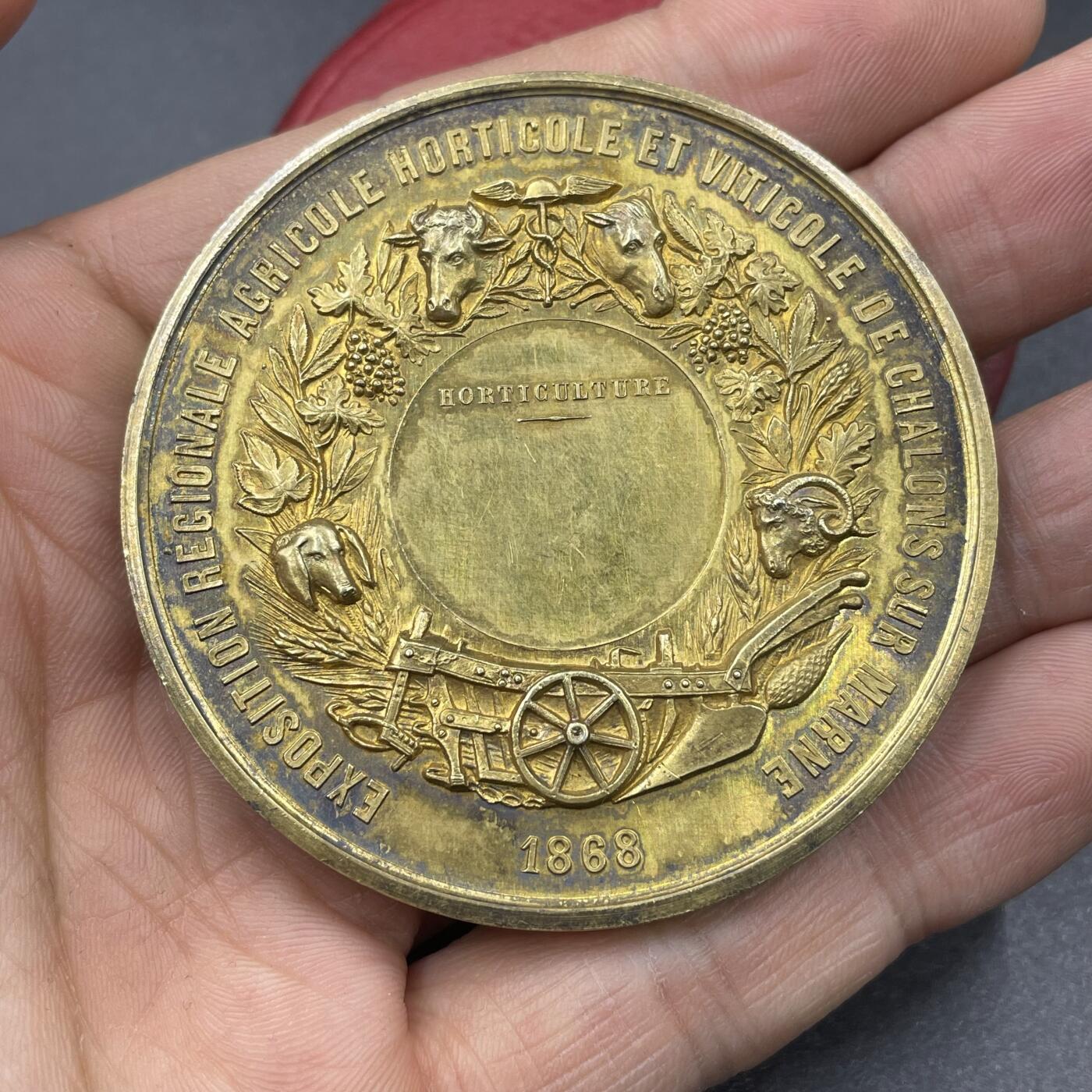 「木头集藏」“冬至雅藏”——章牌精品专场！ A.MERLEY.F～1868年法国马恩河畔沙隆地区农业、园艺与葡萄种植博览会原盒镀金大银章，直径：57.2 mm，88.2 g，边铭：蜜蜂 ARGENT，品相很不错，原盒正常扣合（打开略吃力），章面装饰有牛、马、羊等牲畜头雕，搭配葡萄藤、麦穗等农业元素，还有犁、车轮等农具图案，正中刻有“HORTICULTURE”（园艺），直观体现博览会聚焦农业、园艺与葡萄种植的主题。