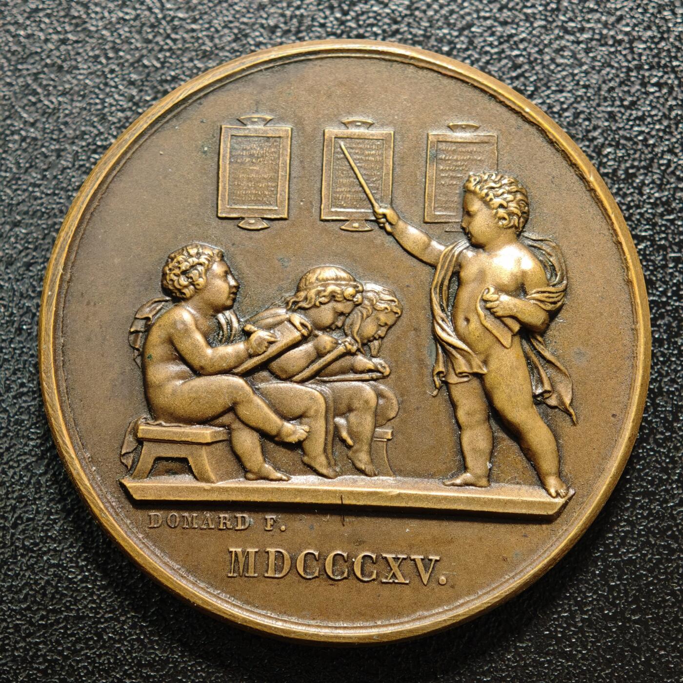 【德藏】世界币章拍卖第158期（拍品征集中~欢迎藏友联系） 1907年 法国初级教育协会纪念铜章，1815年版本，正面是三个坐着的小孩子正在书写板上做记录，站着天使指着墙上挂着的三块中间的牌子正在教导他们；背面是月桂和橡木枝组成的花环和铭文 直径约：41.2mm；重约：37.6g