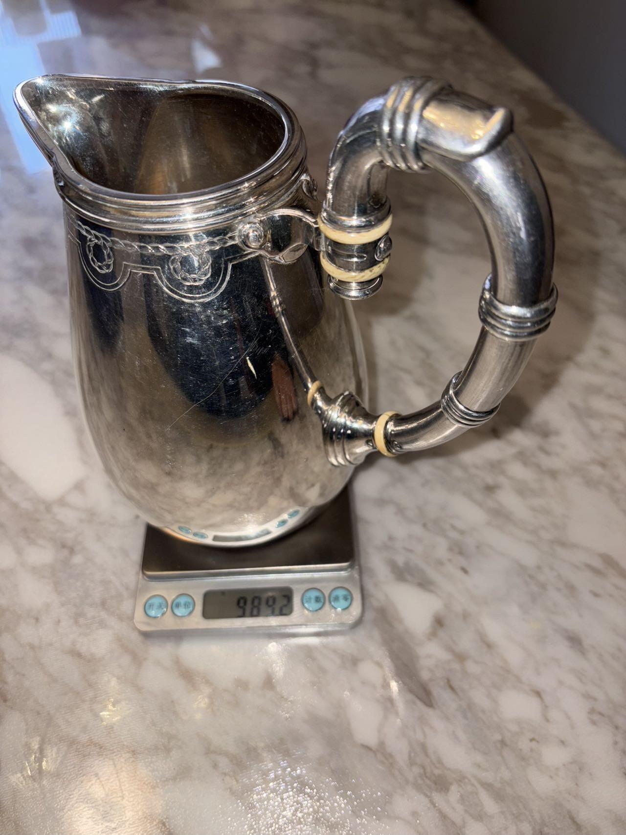 盛世勋华——号角文化勋章邮票专场拍卖第294期 意大利王国皇家海军1941年军官定制银壶，重989克，由米兰知名工坊Broggi打造，执壶通高220毫米（含把手），采用银制工艺打造（部分镀银），器身经精细錾刻与抛光处理，线条流畅饱满，呈现出优雅的梨形轮廓。壶身饰有意大利皇家海军专属纹章与航海主题装饰纹样，底座有银标和厂标