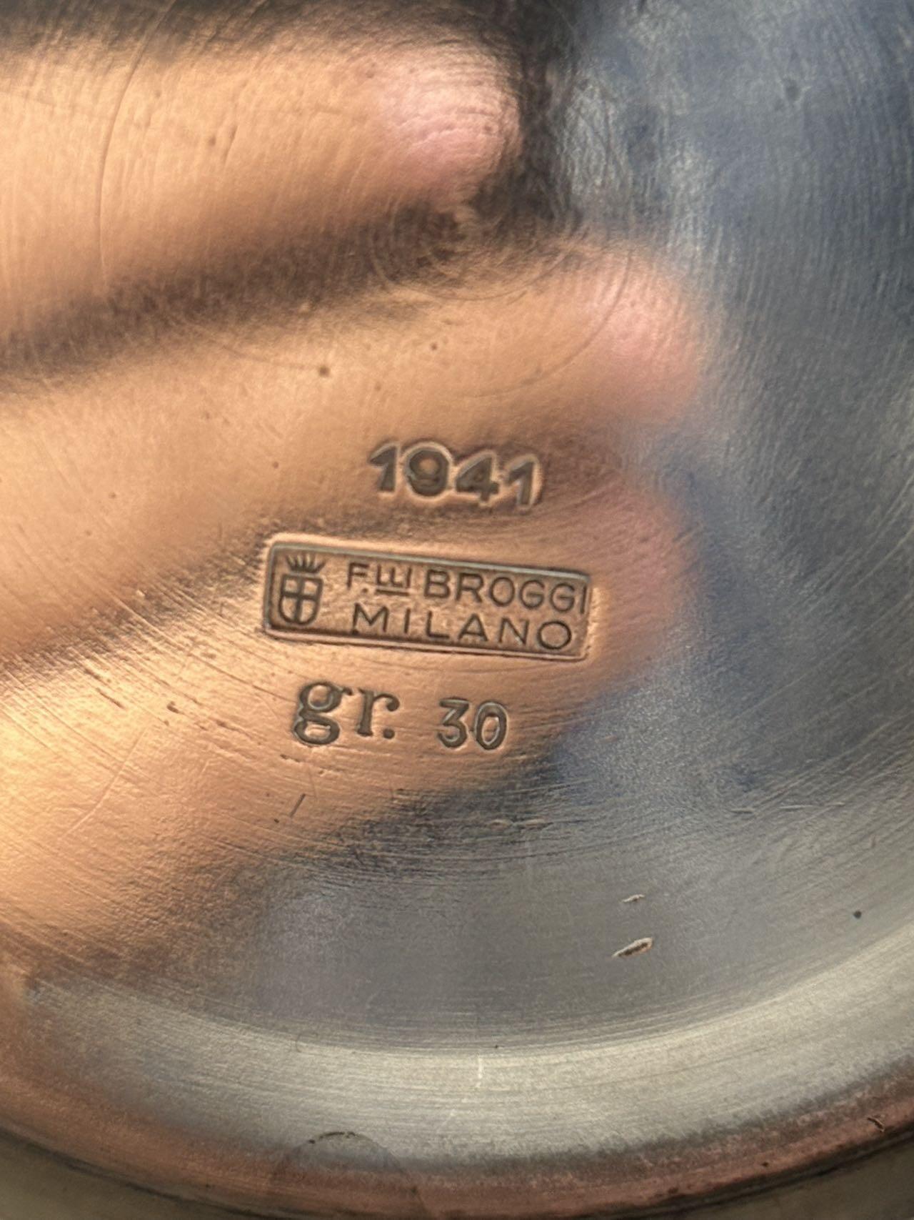 盛世勋华——号角文化勋章邮票专场拍卖第294期 意大利王国皇家海军1941年军官定制银壶，重989克，由米兰知名工坊Broggi打造，执壶通高220毫米（含把手），采用银制工艺打造（部分镀银），器身经精细錾刻与抛光处理，线条流畅饱满，呈现出优雅的梨形轮廓。壶身饰有意大利皇家海军专属纹章与航海主题装饰纹样，底座有银标和厂标