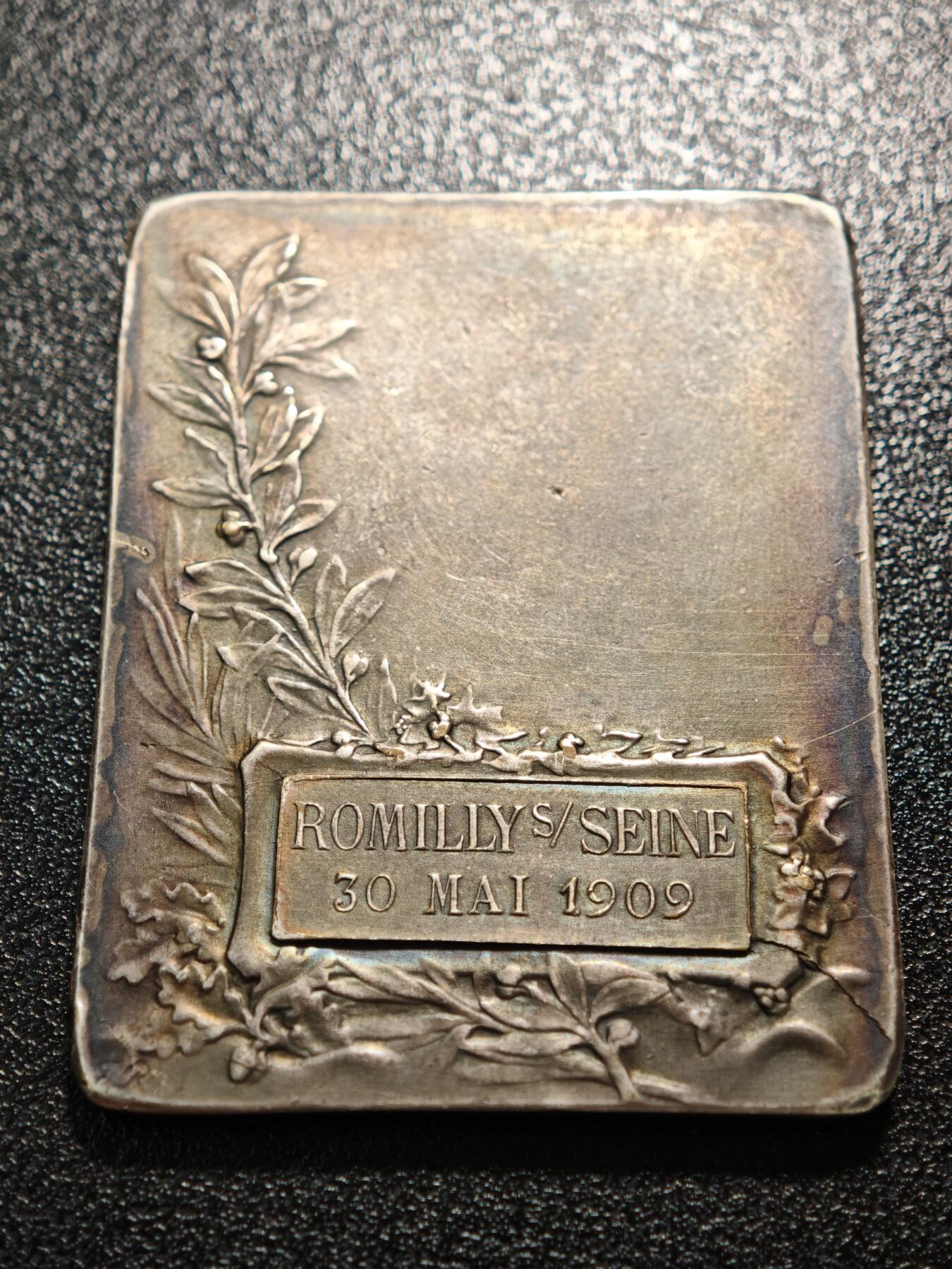 【德藏】世界币章拍卖第158期（拍品征集中~欢迎藏友联系） 1909年 法国塞纳河畔罗米利音乐主题矩形镀银纪念章 由法国新艺术时期铸章师设计打造，是为当地音乐活动颁发的荣誉表彰牌 塞纳河畔罗米利（Romilly-sur-Seine）是法国香槟-阿登地区的城市，1909年当地举办音乐赛事或庆典活动，此纪念牌作为荣誉奖品颁发给优秀的音乐从业者/参赛者，是法国地方文化艺术活动的实物见证 深五彩包浆 直径约：39.4mm×50mm；重约：44.1g