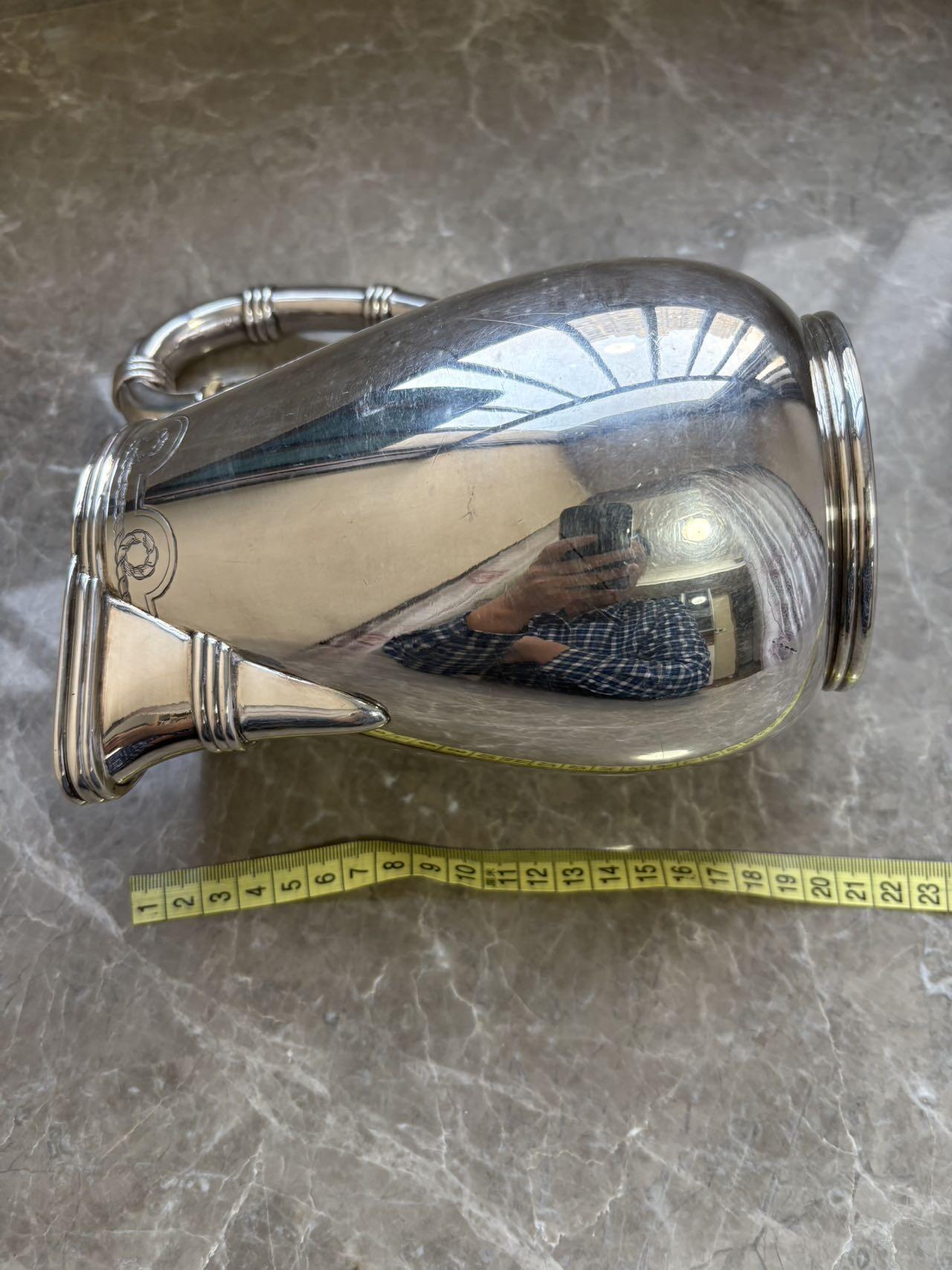 盛世勋华——号角文化勋章邮票专场拍卖第294期 意大利王国皇家海军1941年军官定制银壶，重989克，由米兰知名工坊Broggi打造，执壶通高220毫米（含把手），采用银制工艺打造（部分镀银），器身经精细錾刻与抛光处理，线条流畅饱满，呈现出优雅的梨形轮廓。壶身饰有意大利皇家海军专属纹章与航海主题装饰纹样，底座有银标和厂标