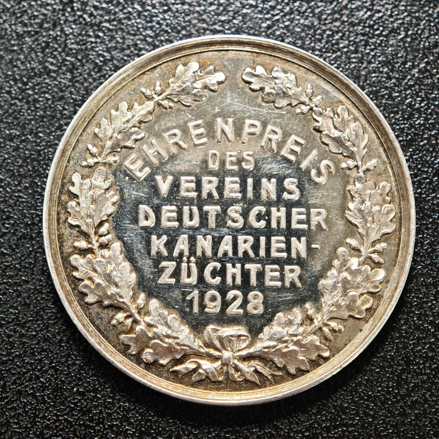 【德藏】世界币章拍卖第158期（拍品征集中~欢迎藏友联系） 1928年 德国金丝雀饲养者协会荣誉奖章纪念银章 由德国造币机构铸造，是该协会为表彰金丝雀繁育领域杰出贡献者颁发的荣誉奖章 德国是欧洲金丝雀繁育的核心地区之一，19世纪起形成专业的饲养者协会，聚焦金丝雀的品种培育、鸣唱训练等领域，这类奖章是行业内认可繁育者成就的重要凭证 直径约：35.2mm；重约：17.3g