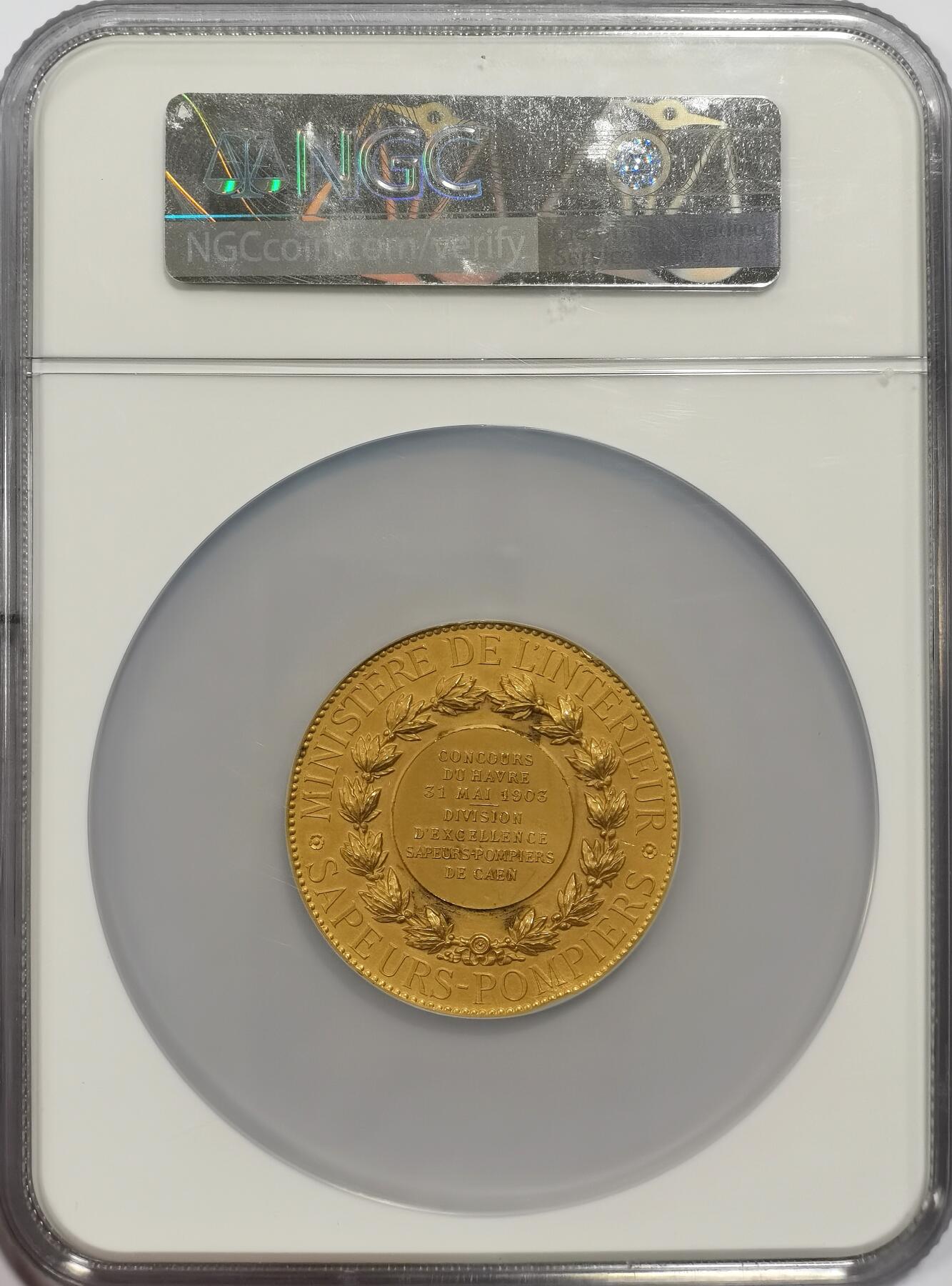 博洋堂世界钱币拍卖第153期（全场包邮） NGC MS63 1903年法国卡昂消防局金质奖章，章牌名家dubois作品，50mm，质量94.77克。正面：三名消防员驾驶消防车驶向燃烧的建筑物；背面：月桂花环内有七行法语铭文；花环外环绕铭文。这枚色彩艳丽、引人注目的金质奖章旨在纪念卡昂消防局在比赛中的英勇表现，细节清晰，光泽柔和近乎哑光。以精美的金质材质，向消防事业致敬。