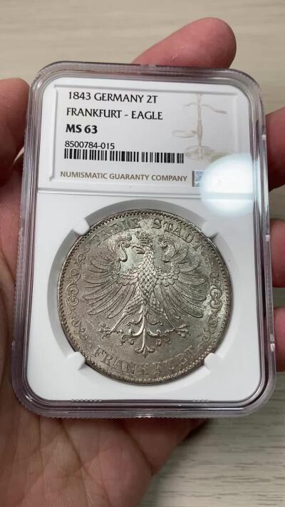 万国钱币拍卖第058期（万国新年大拍） NGC MS63 1843年法兰克福自由市鹰徽流通2泰勒 仅发行12万枚且流通充分 正面是象征法兰克福的雄鹰 背面橡叶结合面值 隔着盒子也能感受到其锋利打制的割手感 华丽淡彩转光 观感超越分数的顶级典藏品质