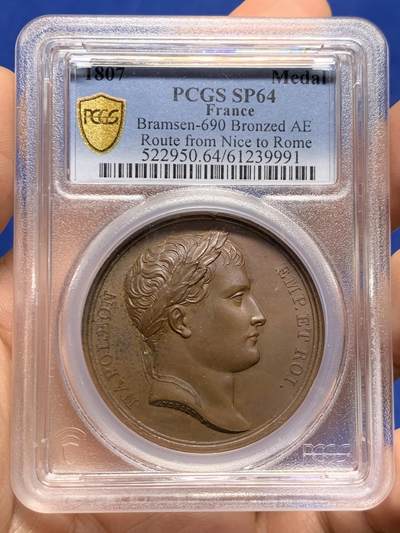 《竞宝斋》第449场 周日，周一，周二  3场连拍 （全场包邮，欢迎送拍） - PCGS SP64 法国1807年拿破仑一世尼斯至罗马之路竣工原铸铜章 巴黎造币厂巧克力包浆 高浮雕原铸铜光 女神维比莉娅（罗马旅行女神）半倚着靠在六辐轮上，一只脚踩在岩石上，另一只脚踩在海面上，轻抬手臂，指明罗马的方向，脚下是罗马道路，背景是群山，画面唯美，条条大道通罗马的实际表现，欧洲最早的“高速公路”通车，标志着拿皇的统治从法国延伸至意大利，辐射整个欧陆。加厚盒
