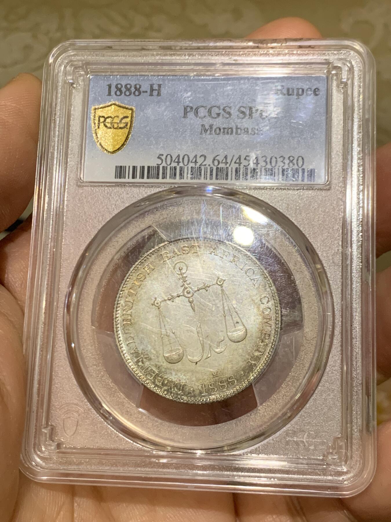 《竞宝斋》第449场 周日，周一，周二  3场连拍 （全场包邮，欢迎送拍） PCGS SP64 蒙巴萨 1888年1卢比银币 PL底板 绚丽五彩包浆 可与不求的状态 蒙巴萨是肯尼亚最大的港口，郑和下西洋最远到达的地方，大热门，吉祥年份 背面支撑小磕
