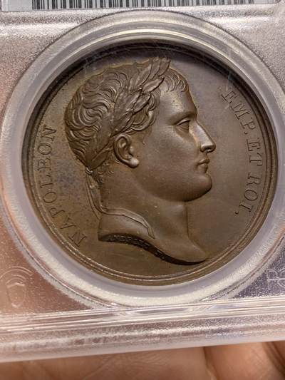 《竞宝斋》第449场 周日，周一，周二  3场连拍 （全场包邮，欢迎送拍） PCGS SP64 法国1807年拿破仑一世尼斯至罗马之路竣工原铸铜章 巴黎造币厂巧克力包浆 高浮雕原铸铜光 女神维比莉娅（罗马旅行女神）半倚着靠在六辐轮上，一只脚踩在岩石上，另一只脚踩在海面上，轻抬手臂，指明罗马的方向，脚下是罗马道路，背景是群山，画面唯美，条条大道通罗马的实际表现，欧洲最早的“高速公路”通车，标志着拿皇的统治从法国延伸至意大利，辐射整个欧陆。加厚盒