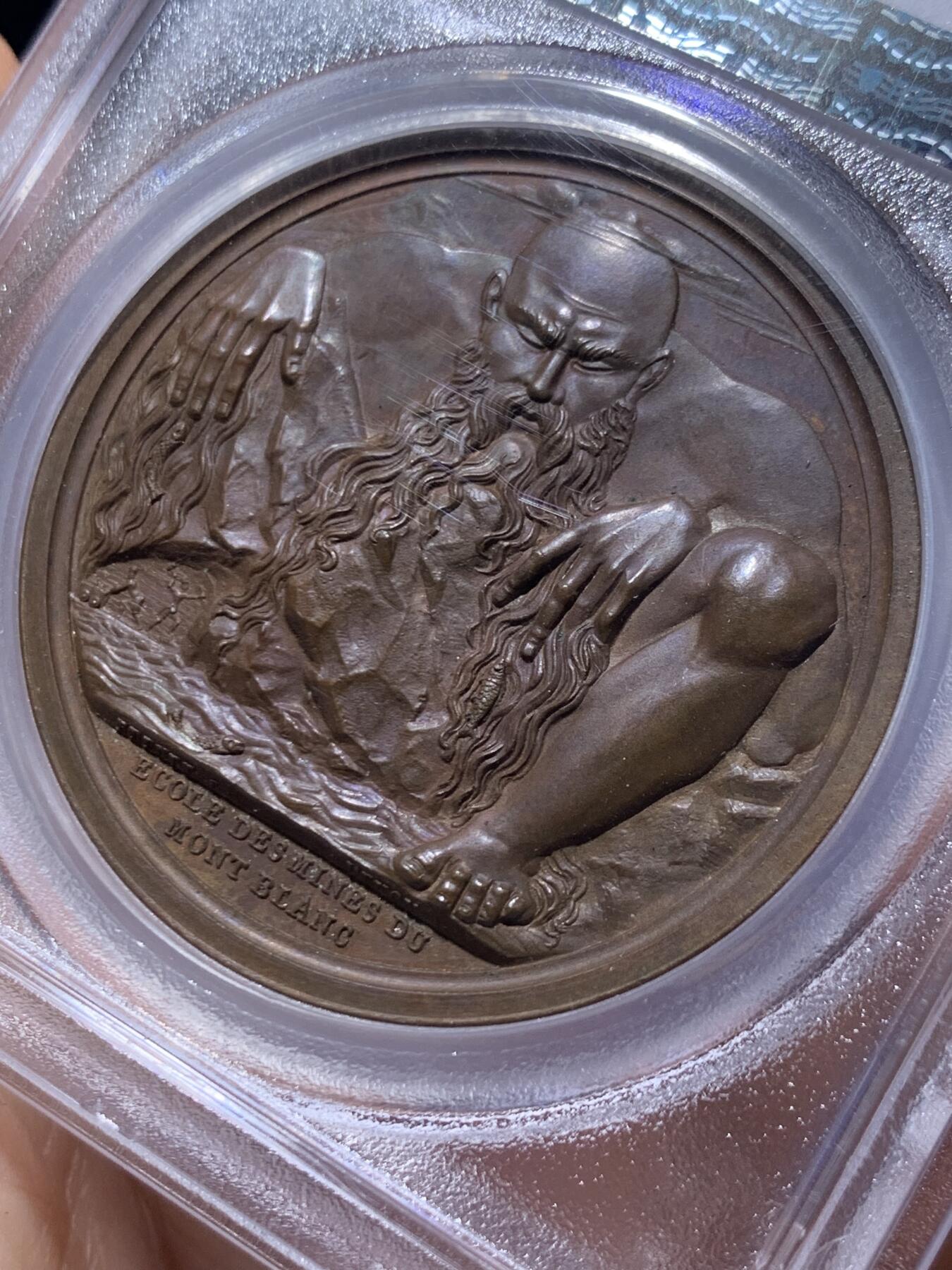 《竞宝斋》第450场 周日，周一，周二  3场连拍 （全场包邮，欢迎送拍） PCGS SP64 亚军分 法国1805年拿破仑一世原铸铜章 拿皇少见头像版 巴黎造币厂紫檀色包浆 勃朗峰拟人化的巨人山神形象，头顶云端，须发缕缕分明，威严充满力量的神明，蹲伏着抬起两名矿工正在工作的巨石，满满细节，脚下是一条流淌的河流，曲折地流淌，可谓拿章系列中画面最富创造力之一，仅一枚65分更高，加厚盒。