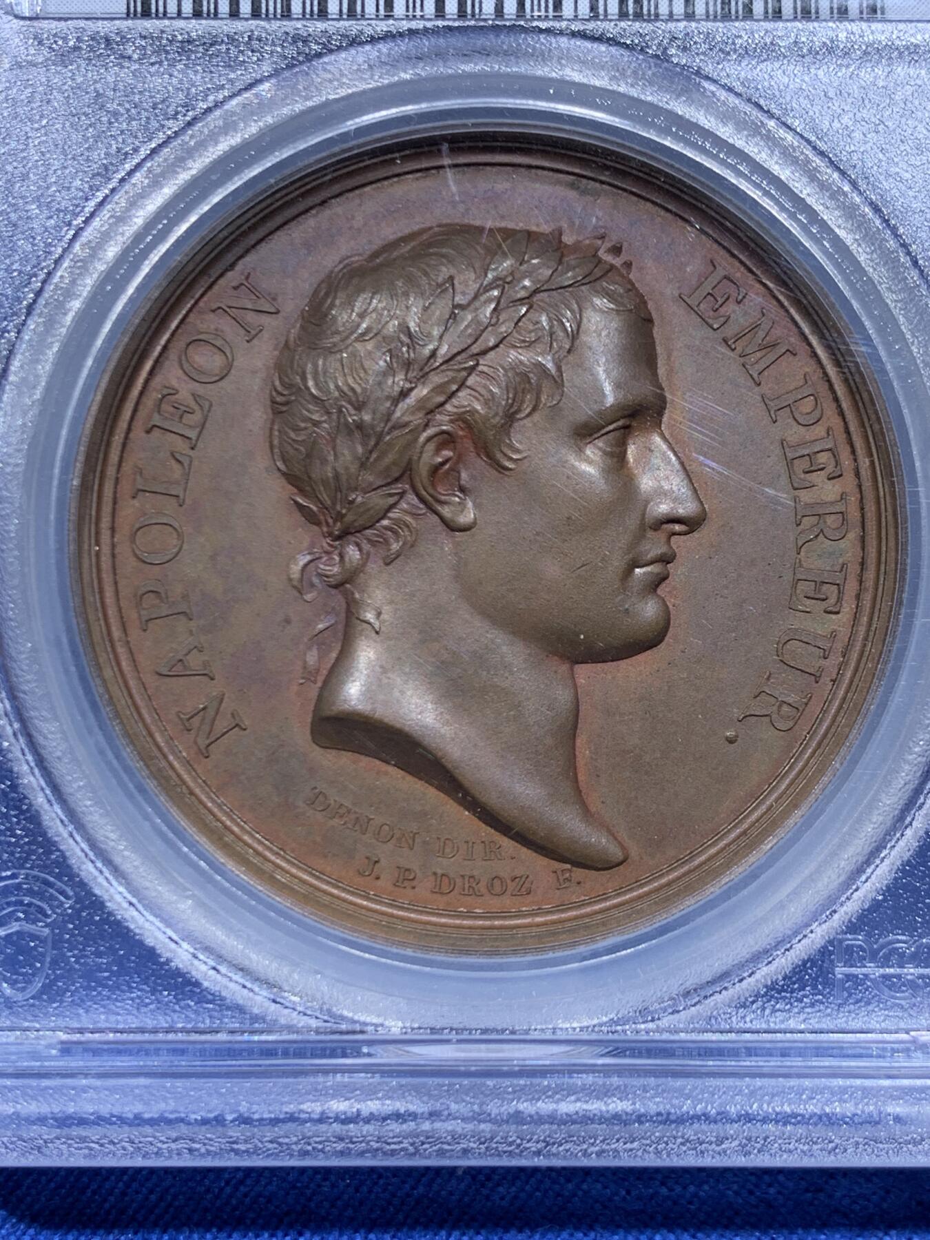 《竞宝斋》第450场 周日，周一，周二  3场连拍 （全场包邮，欢迎送拍） PCGS SP64 亚军分 法国1805年拿破仑一世原铸铜章 拿皇少见头像版 巴黎造币厂紫檀色包浆 勃朗峰拟人化的巨人山神形象，头顶云端，须发缕缕分明，威严充满力量的神明，蹲伏着抬起两名矿工正在工作的巨石，满满细节，脚下是一条流淌的河流，曲折地流淌，可谓拿章系列中画面最富创造力之一，仅一枚65分更高，加厚盒。