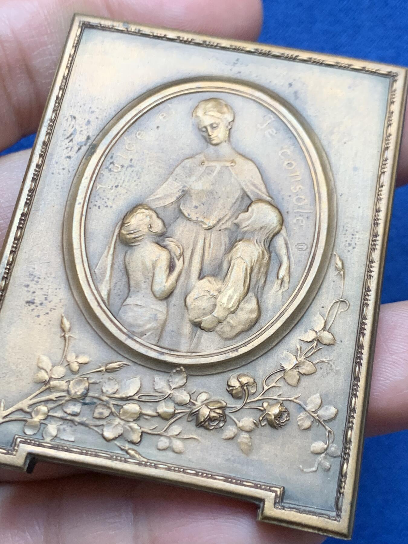 《竞宝斋》第451场 周日，周一，周二  3场连拍 （全场包邮，欢迎送拍） 比利时著名雕刻家：Godefroid Devreese作品-《孤儿之花》艺术奖章，非常漂亮，双面人物雕刻，整体奖章以画框形式展现，极为少见，正面女神展开双臂将儿童拥入怀中，十分暖意。背面一名手提花篮的穿连体短裙的小女儿，手拿花束十分优雅。不可错过。规格：62*46.6mm，重：90.4g