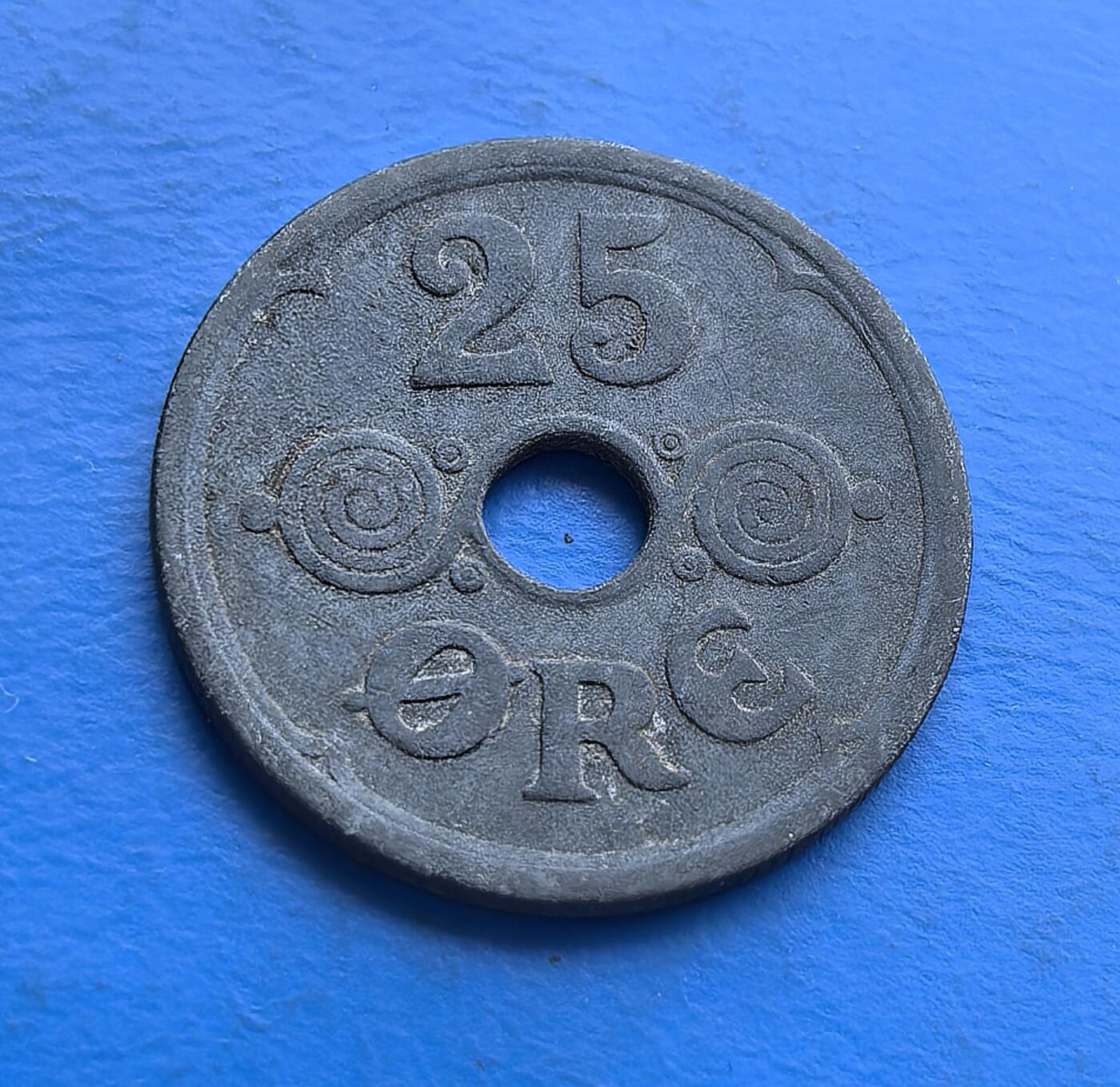 外国优质老铜币高银银币，周六九点倒数截拍，满百包邮，持续收拍 丹麦 1941 年25 欧尔圆孔锌币，铸于二战被占期。正面君主花押（CXR）配皇冠，背面面额嵌螺旋纹，圆孔因资源匮乏而生。锌质包浆凝战时沧桑，见证北欧中立国沦陷下的货币应急。作为二战丹麦币标本，亲民可藏，解码被占期资源困局与王室符号存续 。