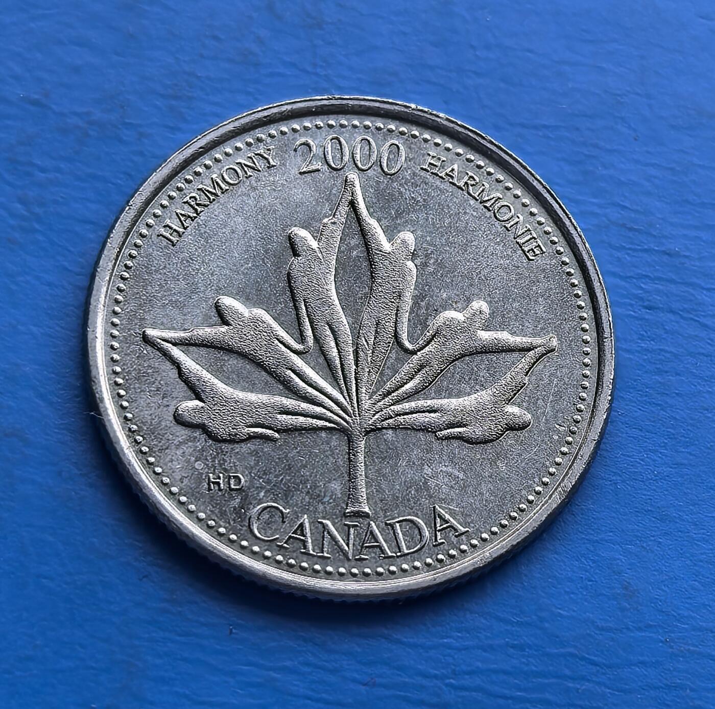 外国优质老铜币高银银币，周六九点倒数截拍，满百包邮，持续收拍 加拿大2000 年25 分千禧纪念币，属 “和谐（HARMONY）” 主题 。背面枫叶由人手交织而成，呼应双语铭文，具象化多元包容的国家精神；正面女王王冠像经典。作为千禧年发行的系列币之一，币面设计巧思与时代印记交融，是收藏加拿大文化内核、见证千禧节点的独特载体 。