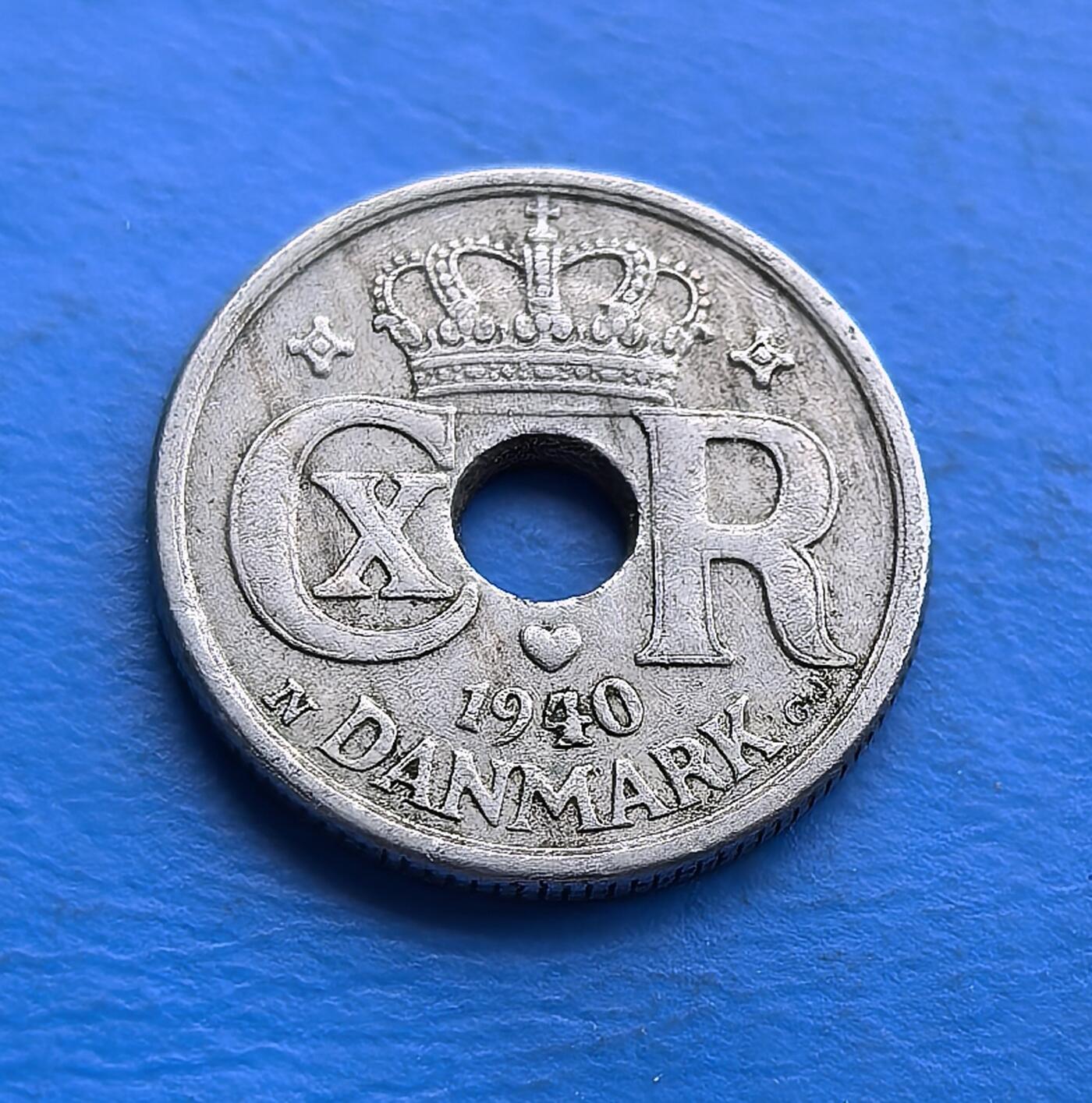 外国优质老铜币高银银币，周六九点倒数截拍，满百包邮，持续收拍 丹麦1940 年10 欧尔圆孔币，铸于二战占领伊始。正面螺旋纹配圆孔，设计复古；背面君主花押（CXR）与皇冠，暗喻王室存续。铜镍包浆凝战时初痕，见证中立国沦陷瞬间。作为被占首年货币，承载战争开端记忆，亲民门槛，适配战争史与北欧币藏，解码战时王权与货币的微妙博弈 。