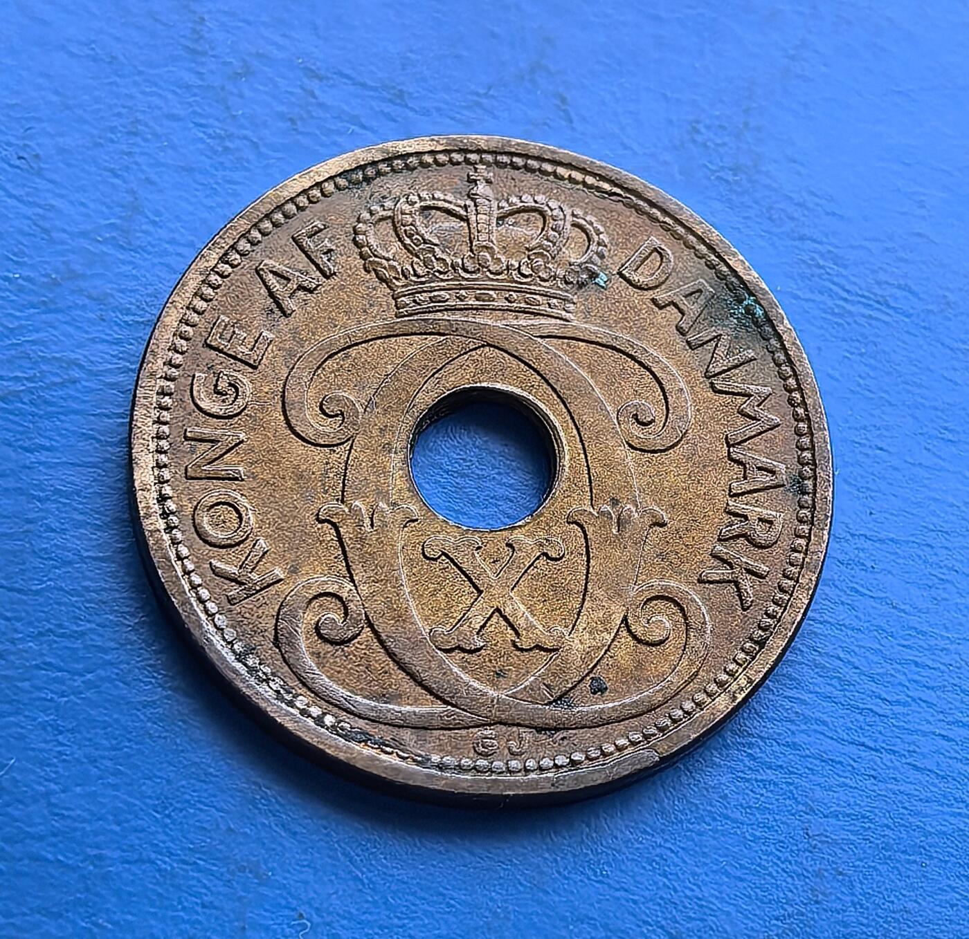 外国优质老铜币高银银币，周六九点倒数截拍，满百包邮，持续收拍 丹麦1940年5 欧尔青铜币，发行于二战丹麦被占领前夕，见证历史转折。独特圆孔设计，正面镌年份与面值，背面饰克里斯蒂安十世王室花押及皇冠 。采用青铜材质（后期因战争改铝 / 锌），包浆厚重，集北欧货币特色、战时过渡背景于一体，是丹麦君主制与二战史收藏的特色标的。