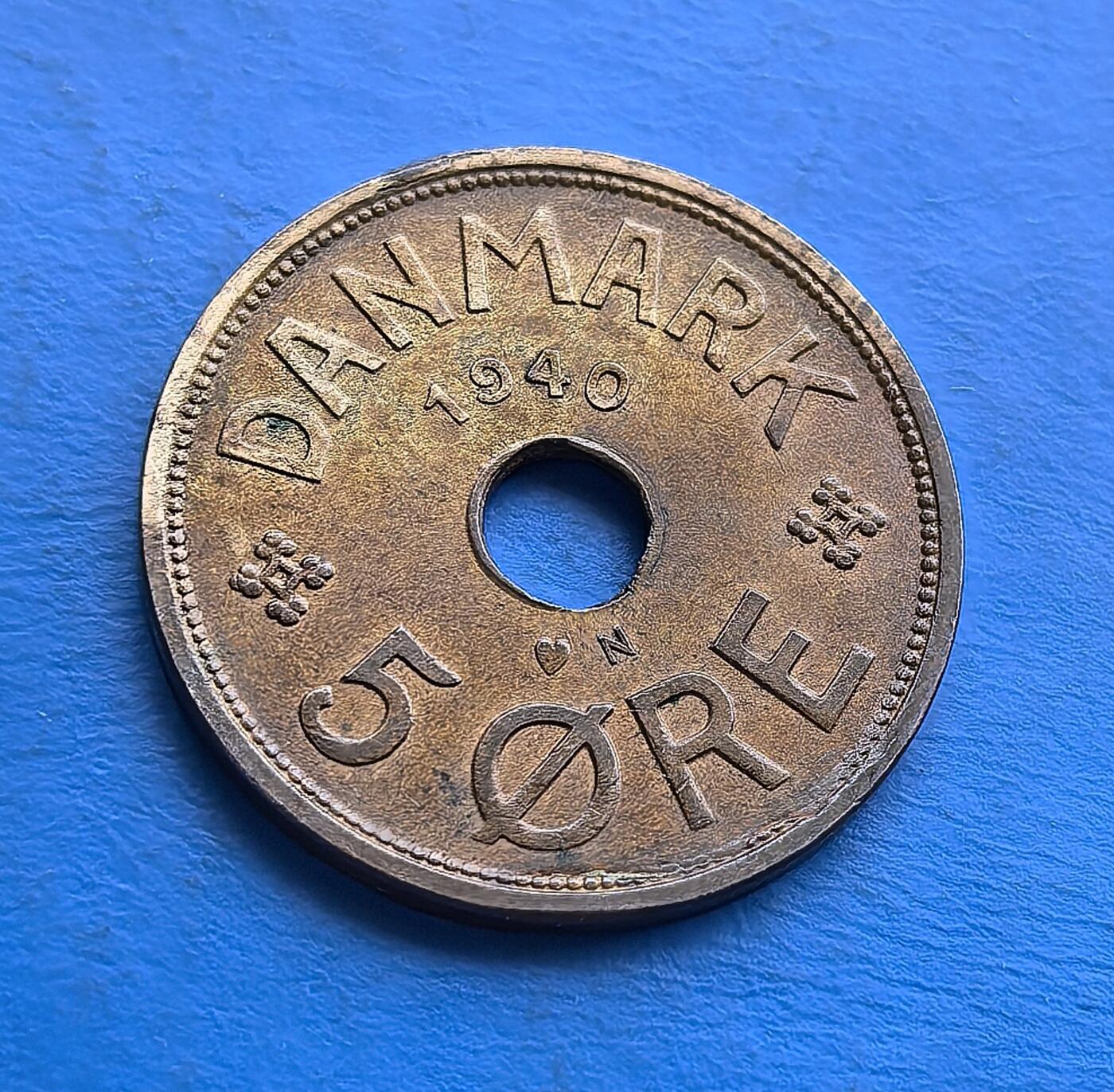 外国优质老铜币高银银币，周六九点倒数截拍，满百包邮，持续收拍 丹麦1940年5 欧尔青铜币，发行于二战丹麦被占领前夕，见证历史转折。独特圆孔设计，正面镌年份与面值，背面饰克里斯蒂安十世王室花押及皇冠 。采用青铜材质（后期因战争改铝 / 锌），包浆厚重，集北欧货币特色、战时过渡背景于一体，是丹麦君主制与二战史收藏的特色标的。