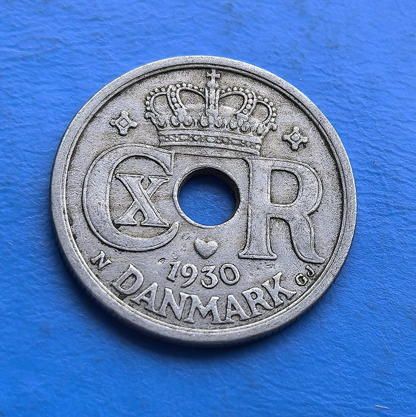 外国优质老铜币高银银币，周六九点倒数截拍，满百包邮，持续收拍 丹麦1930 年 25 欧尔圆孔币，铸于大萧条前夜。正面螺旋纹配圆孔，设计复古别致；背面君主花押（CXR）与皇冠，彰显王室符号。铜镍质地包浆自然，承载战前丹麦货币审美。作为克里斯蒂安十世时期实物，亲民门槛，适配欧洲古币藏家，解码 20 世纪初北欧王室与经济脉络，是小众币藏的特色标的 。
