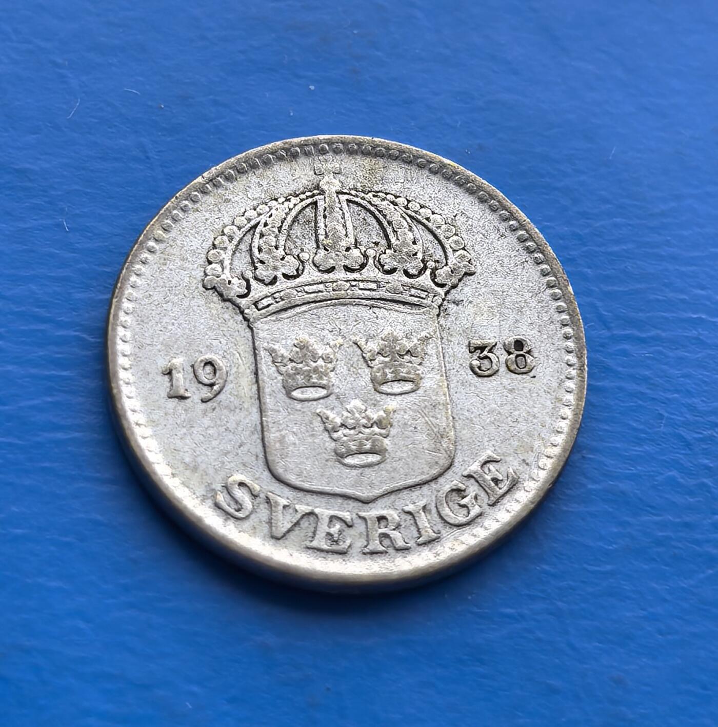 外国优质老铜币高银银币，周六九点倒数截拍，满百包邮，持续收拍 瑞典1938 年25 欧尔银币，正面镌王室皇冠与三王冠盾徽（瑞典千年王权象征），背面橄榄枝环饰（呼应北欧和平传统）。银质基底，历经八十余载包浆温润。发行于二战前夕，承载北欧中立史脉。设计凝练王室威严与和平寓意，是瑞典钱币体系中连接传统与现代的标本，适配北欧币藏家、王室符号爱好者，及研究战前欧洲货币文化的历史追梦者 。