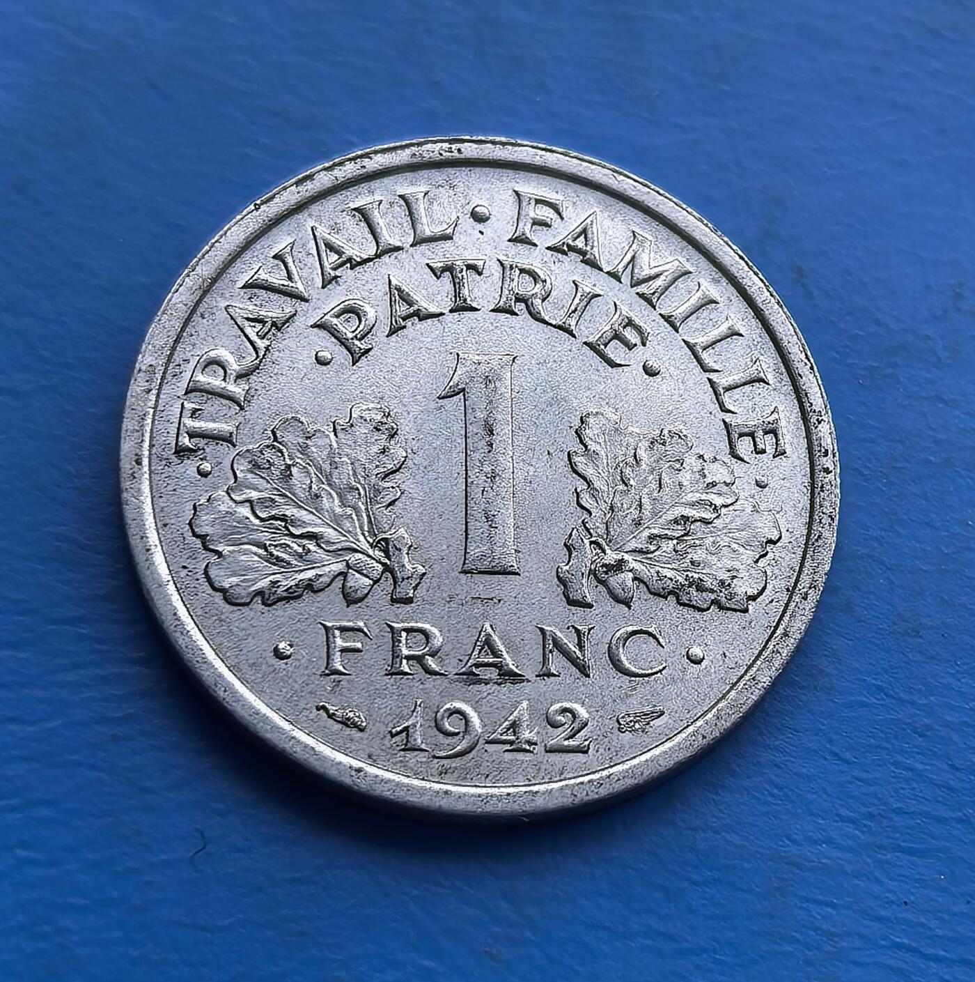 外国优质老铜币高银银币，周六九点倒数截拍，满百包邮，持续收拍 少见束棒星星清晰可见，1942 年维希法国 1 法郎币，铸于二战沦陷期。正面 “工作・家庭・祖国” 彰显政权意识形态，背面斧与麦穗（维希符号）。铝质包浆凝战时沧桑，承载被占区货币史与政治隐喻。作为二战特殊时期实物，亲民门槛，适配战争史藏家，解码法国战时复杂脉络 。