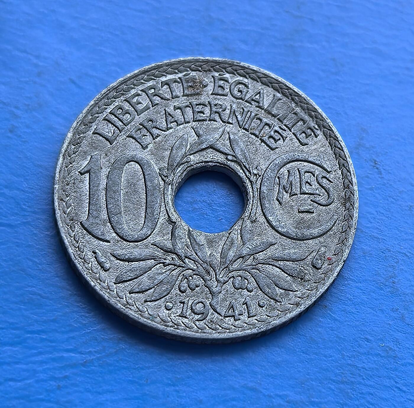 外国优质老铜币高银银币，周六九点倒数截拍，满百包邮，持续收拍 法国维希政权1941 年 10 生丁圆孔币，铸于二战沦陷期。正面镌共和理念 “自由平等博爱”，背面 “RF” 配头盔（战时符号），圆孔设计因物资短缺而生。承载法国黑暗岁月记忆，见证特殊时期货币简化，是二战欧洲被占史的实物标本，亲民门槛解码战时经济与政治脉络 。