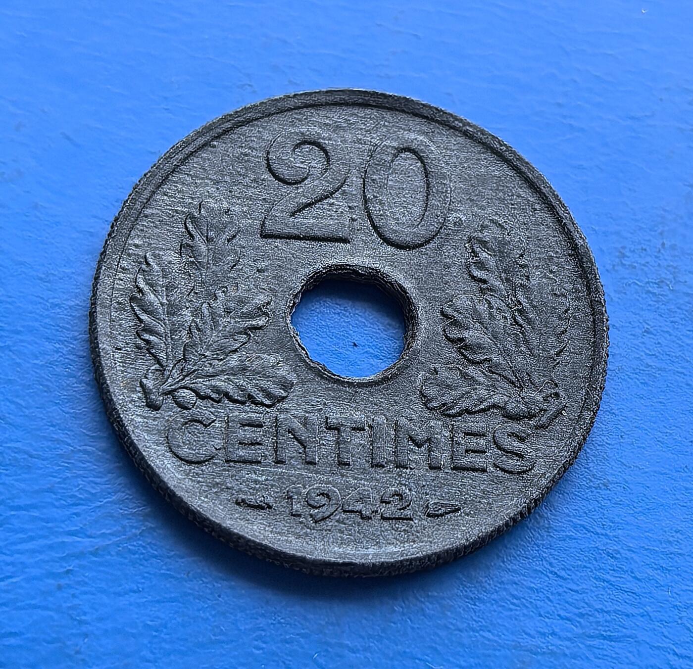 外国优质老铜币高银银币，周六九点倒数截拍，满百包邮，持续收拍 维希法国1942 年 20 生丁圆孔币，铸于二战沦陷期。正面 “ETAT FRANCAIS” 彰显政权符号，背面橡叶环护面额，圆孔设计因物资匮乏而生。劣质材质凝岁月痕，承载战时经济困局与维希时代印记，是二战被占区货币的微观标本，亲民门槛解码法国黑暗岁月的货币脉络 。