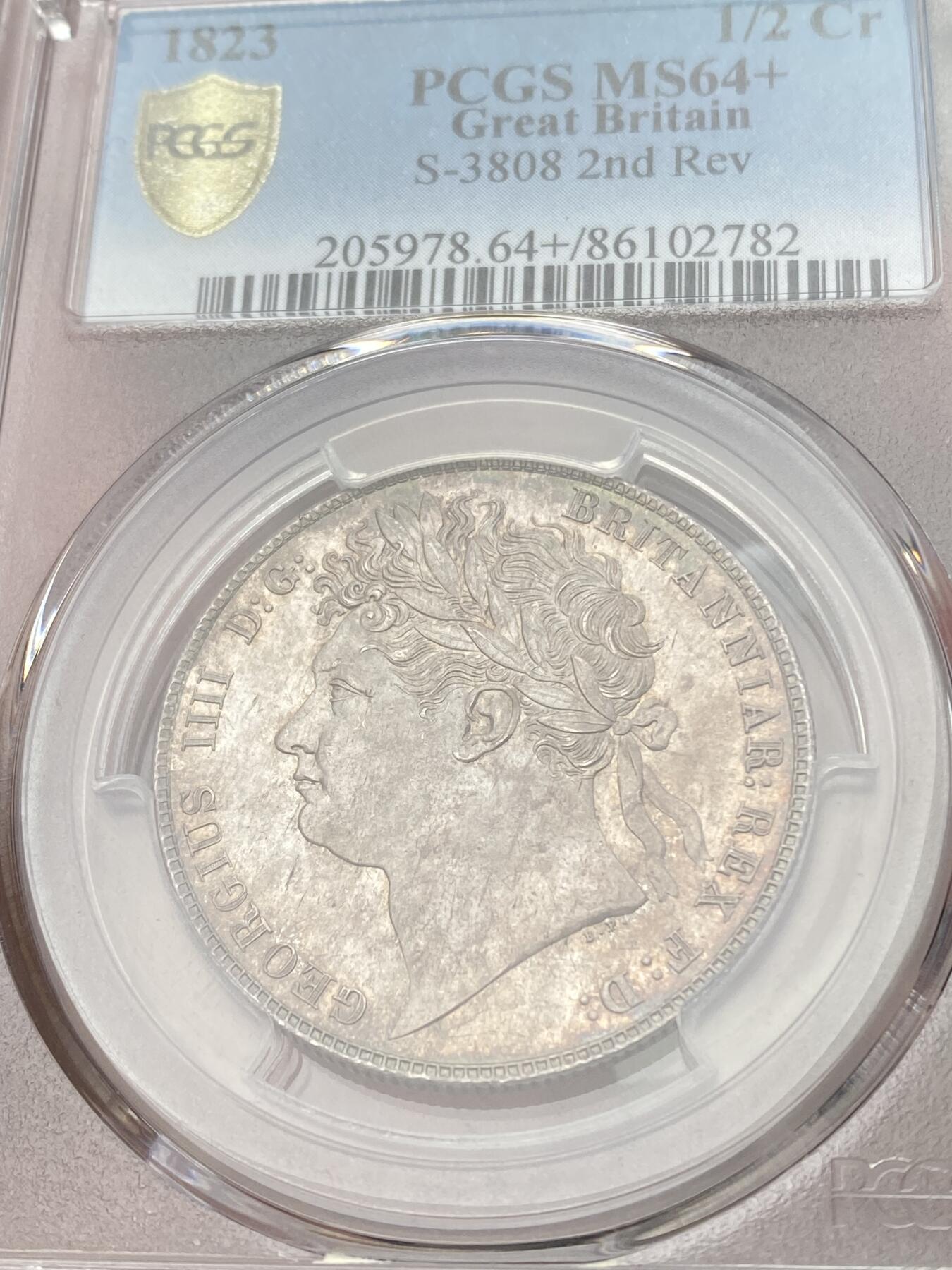 万国钱币拍卖第058期（万国新年大拍） PCGS MS64+ 1823年英国乔治四世嘉德纹章版半克朗银币 嘉德纹章版 乔四流通半克朗中难度最大的一款 PC亚军分 更高分仅一枚 优雅青灰包浆车轮转光 一步到位的典藏级品质