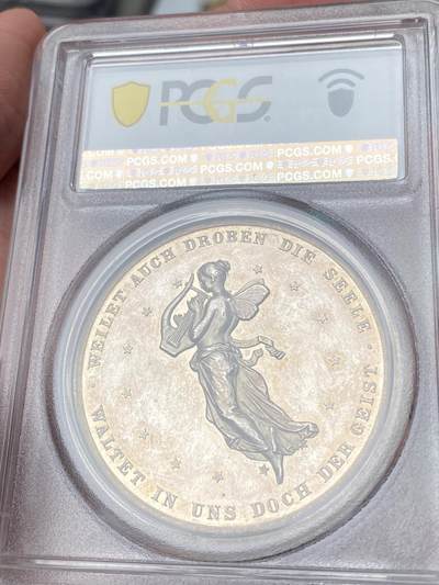 万国钱币拍卖第058期（万国新年大拍） PCGS MS63 1859年德国席勒诞辰百年纪念银章 PC唯一评级记录冠军分 稀见品种 43mm 28.8g 精制工艺强镜面，超高浮雕加厚盒。loos工坊大师炫技之作。雕刻细节极佳，人物栩栩如生。实物非常漂亮。正面:桂冠诗人席勒头像。背面:带翼缪斯女神手里拿着竖琴在天空飞行，13颗星星环绕。圣灵守护我们，灵魂也在其中徘徊。天使小翅膀灵动可爱又迷人。欧盟的盟歌欢乐颂为席勒于1785年创作的诗歌。